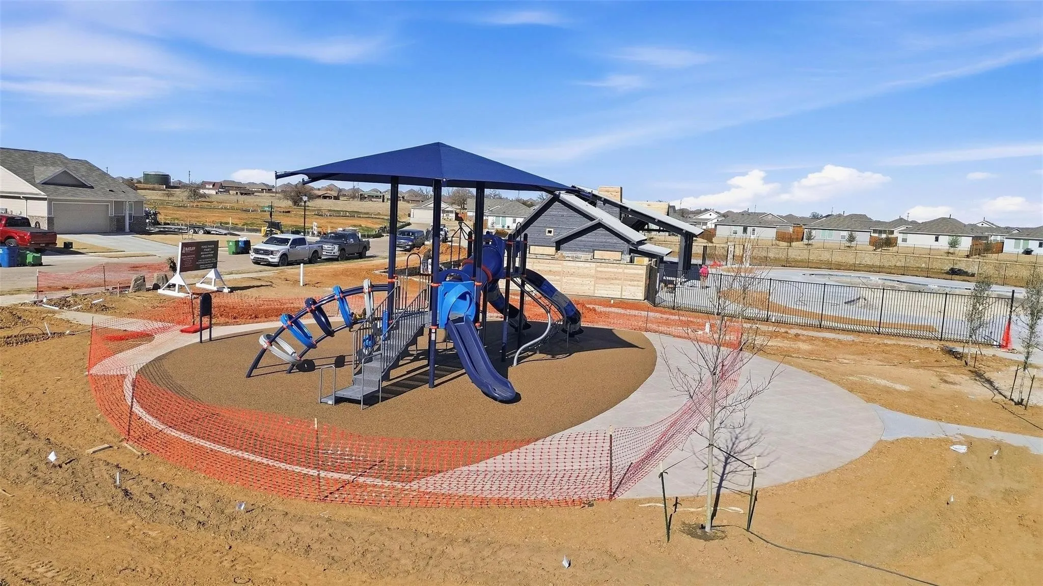 Modern playground structure featuring multiple slides, climbing elements, and a protective shade canopy