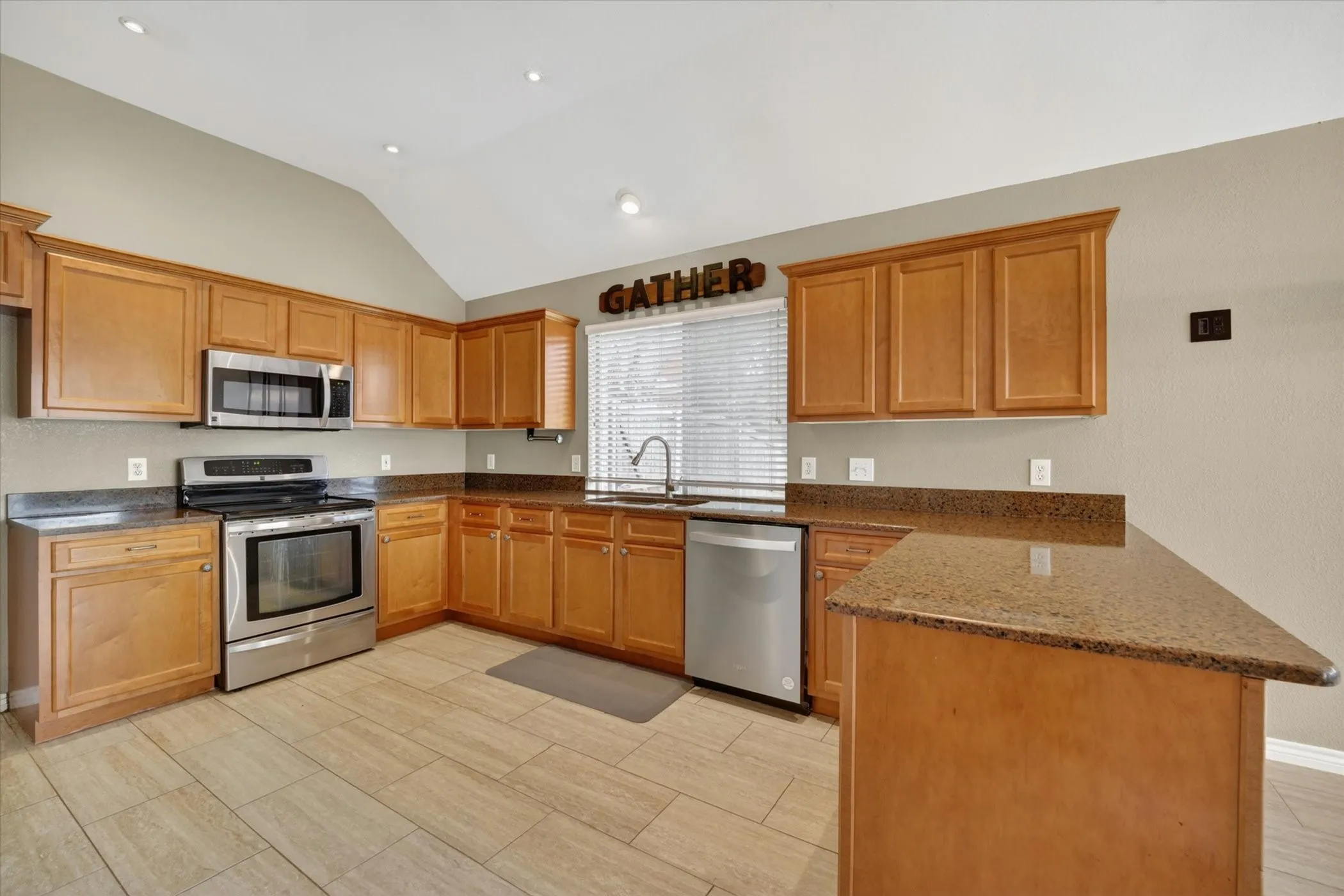 Kitchen featuring wood cabinetry, stainless steel appliances, and stone-finish countertops