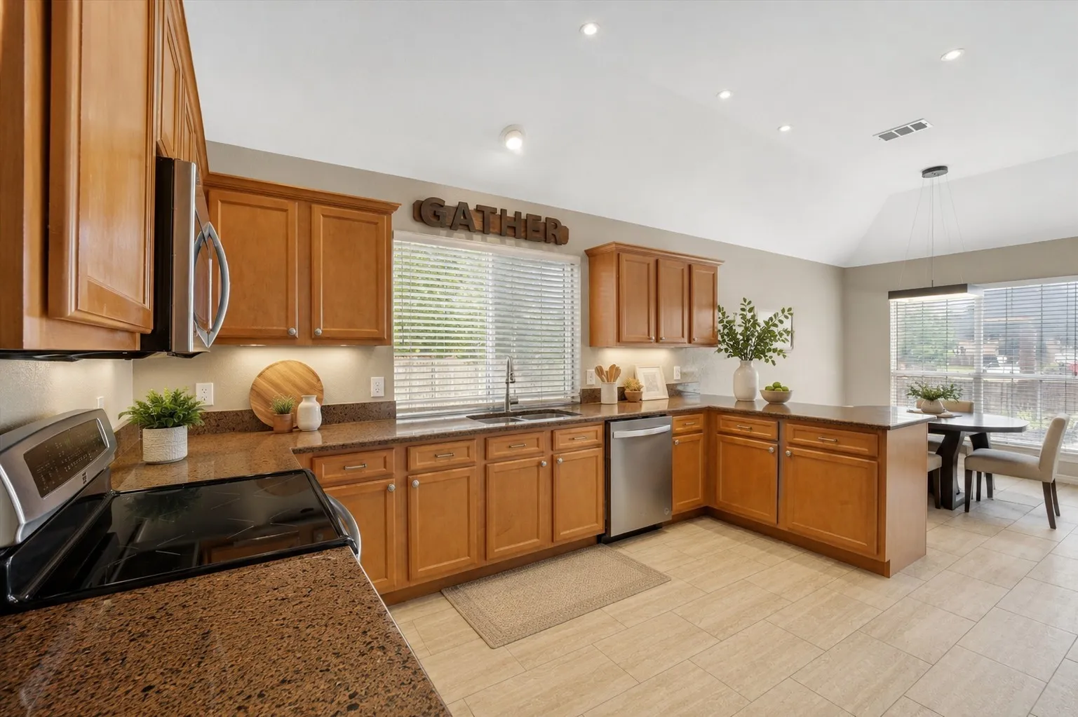 Kitchen featuring wood cabinetry, granite-style countertops, stainless steel appliances, and tile flooring
