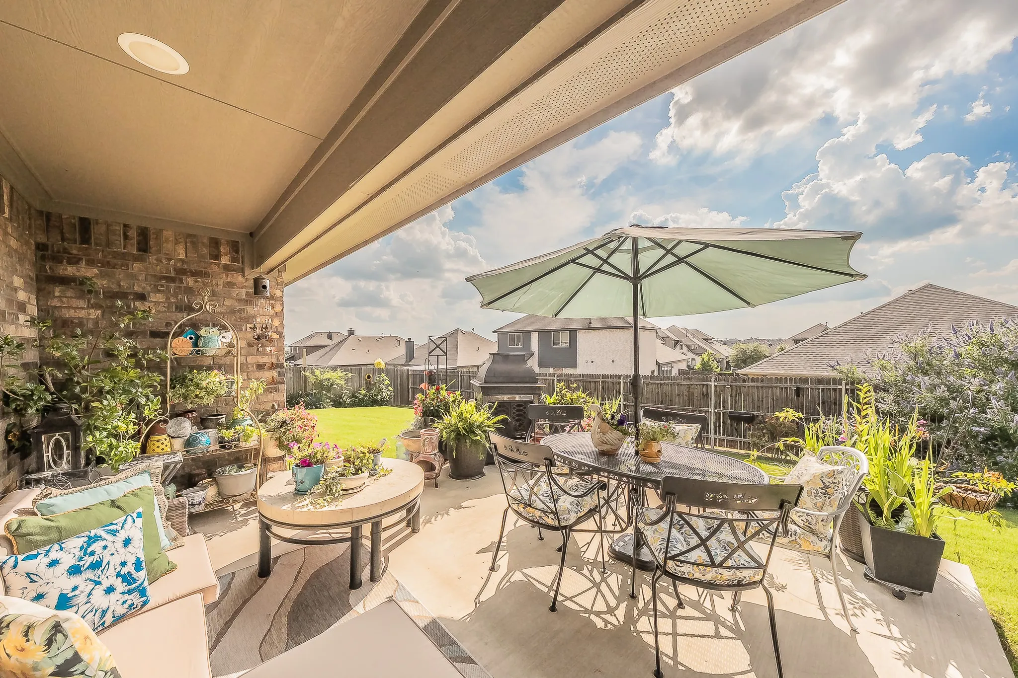 Expansive covered patio featuring a concrete surface, brick exterior wall, and integrated ceiling lighting