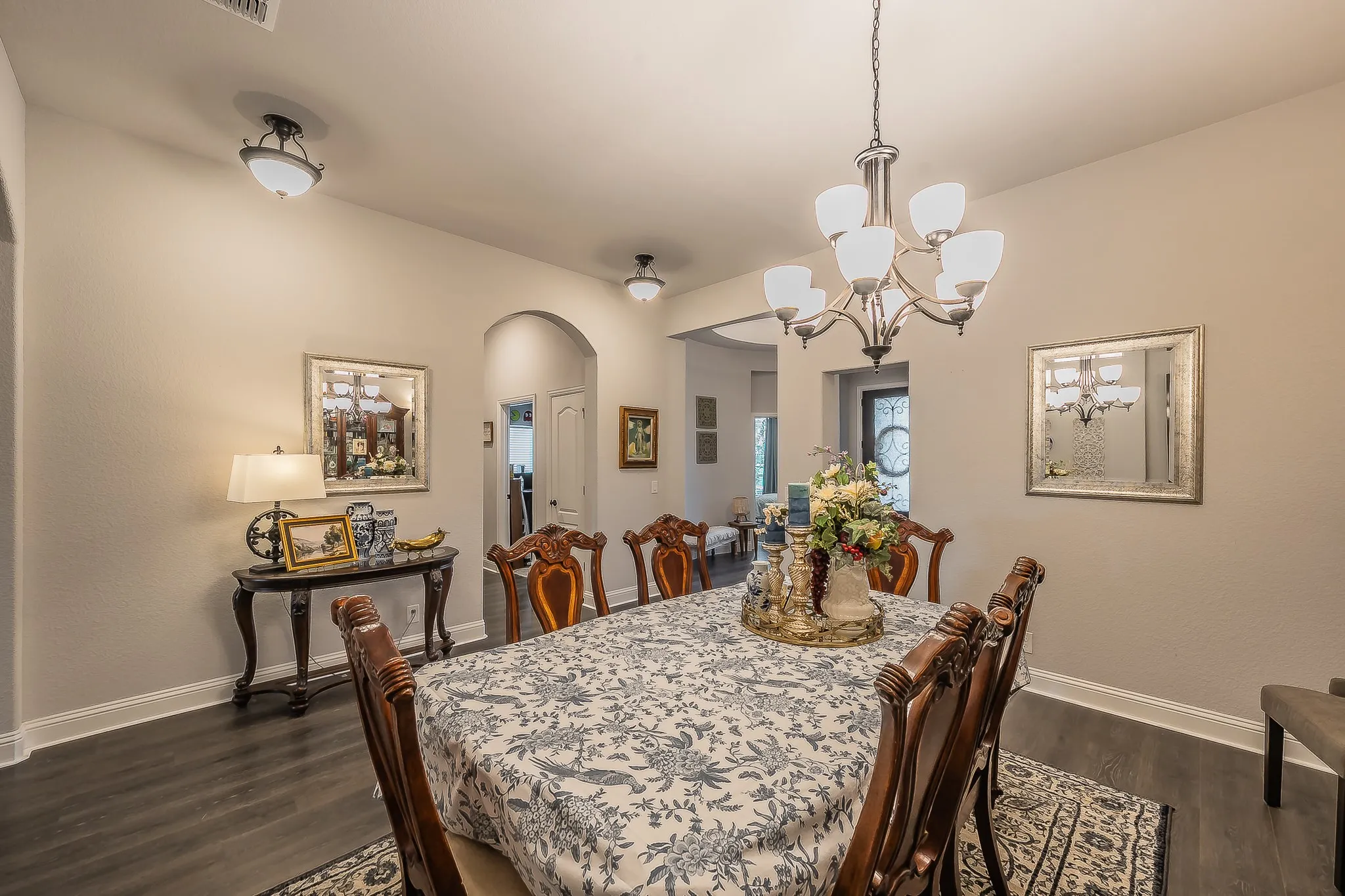 Formal dining space featuring dark wood-finish flooring, a traditional chandelier, recessed lighting, and an arched doorway