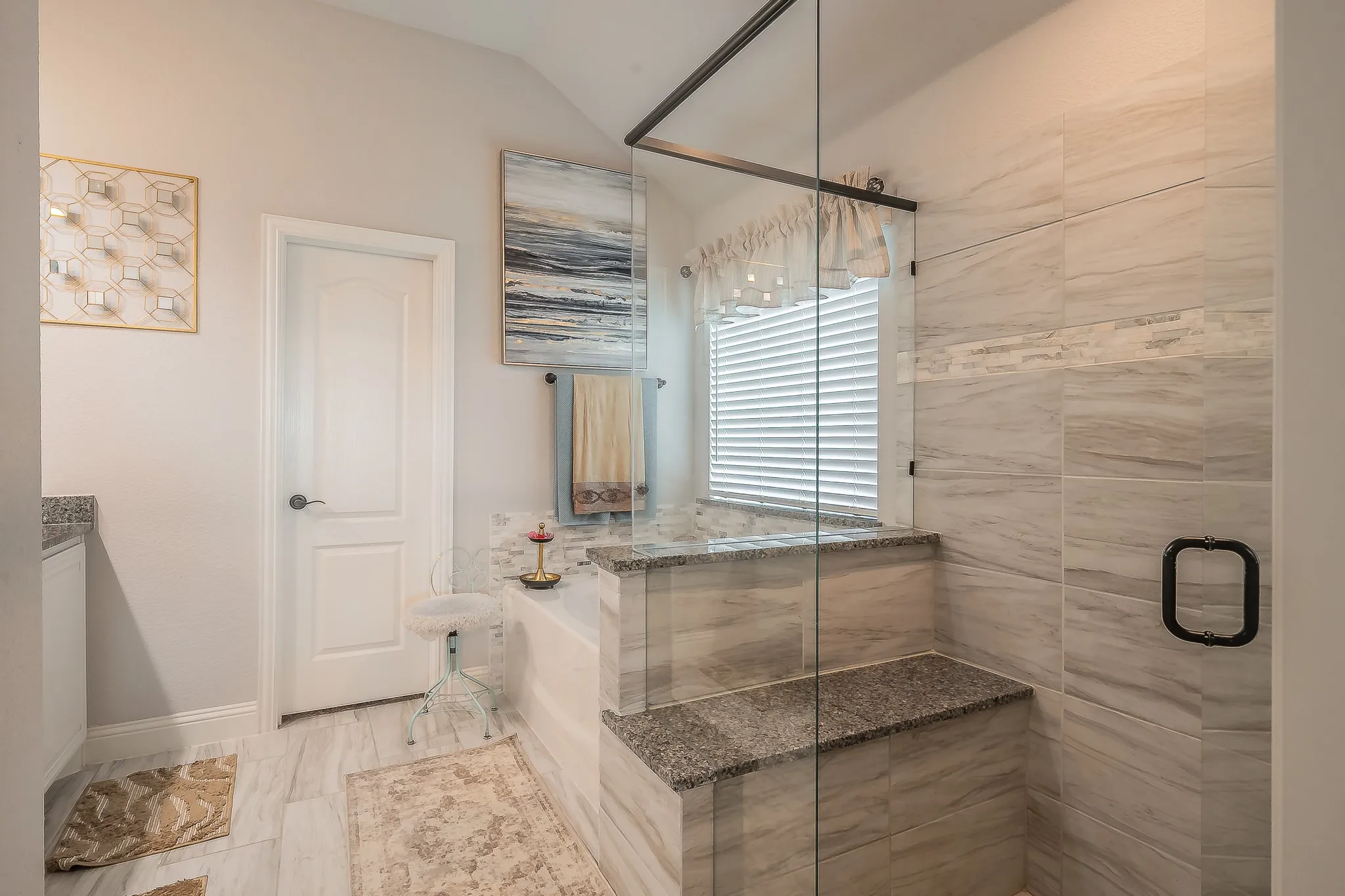 Spacious shower enclosure with glass surround, integrated bench seating, and light-toned tilework