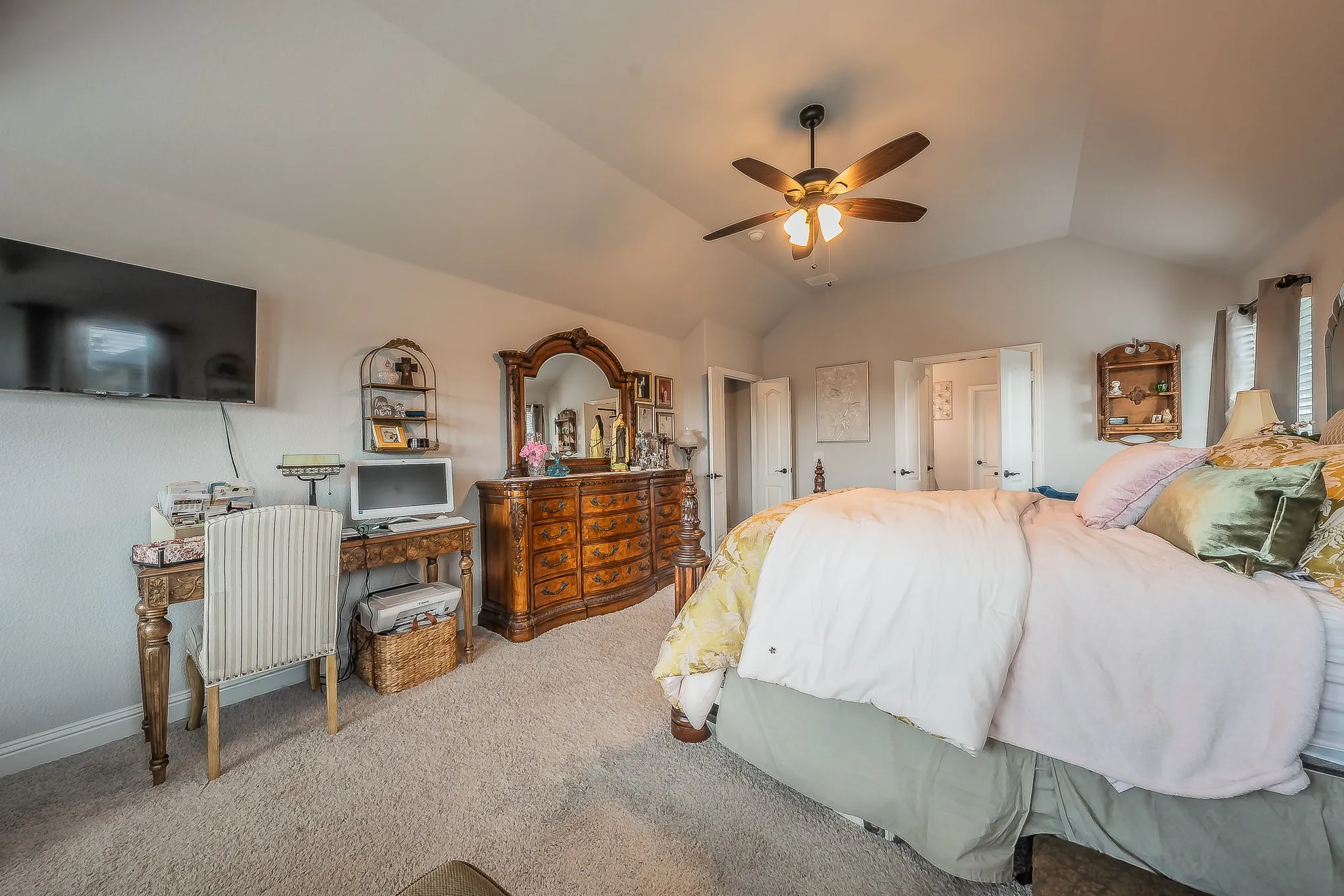 Carpeted interior space featuring a vaulted ceiling with a ceiling fan