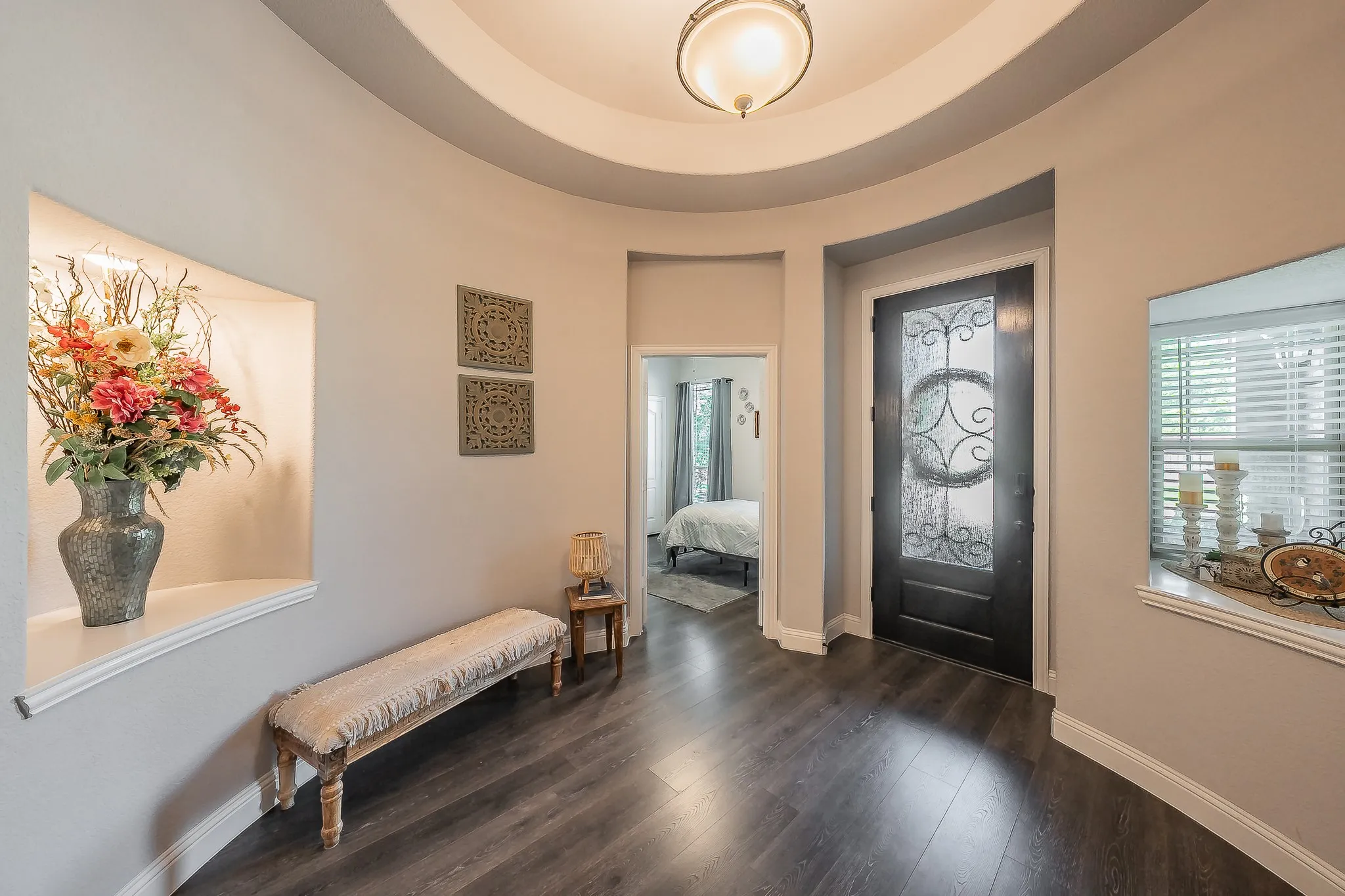 Entryway featuring a dark wood-finish door with decorative glass, recessed wall niches, and wood-finish flooring
