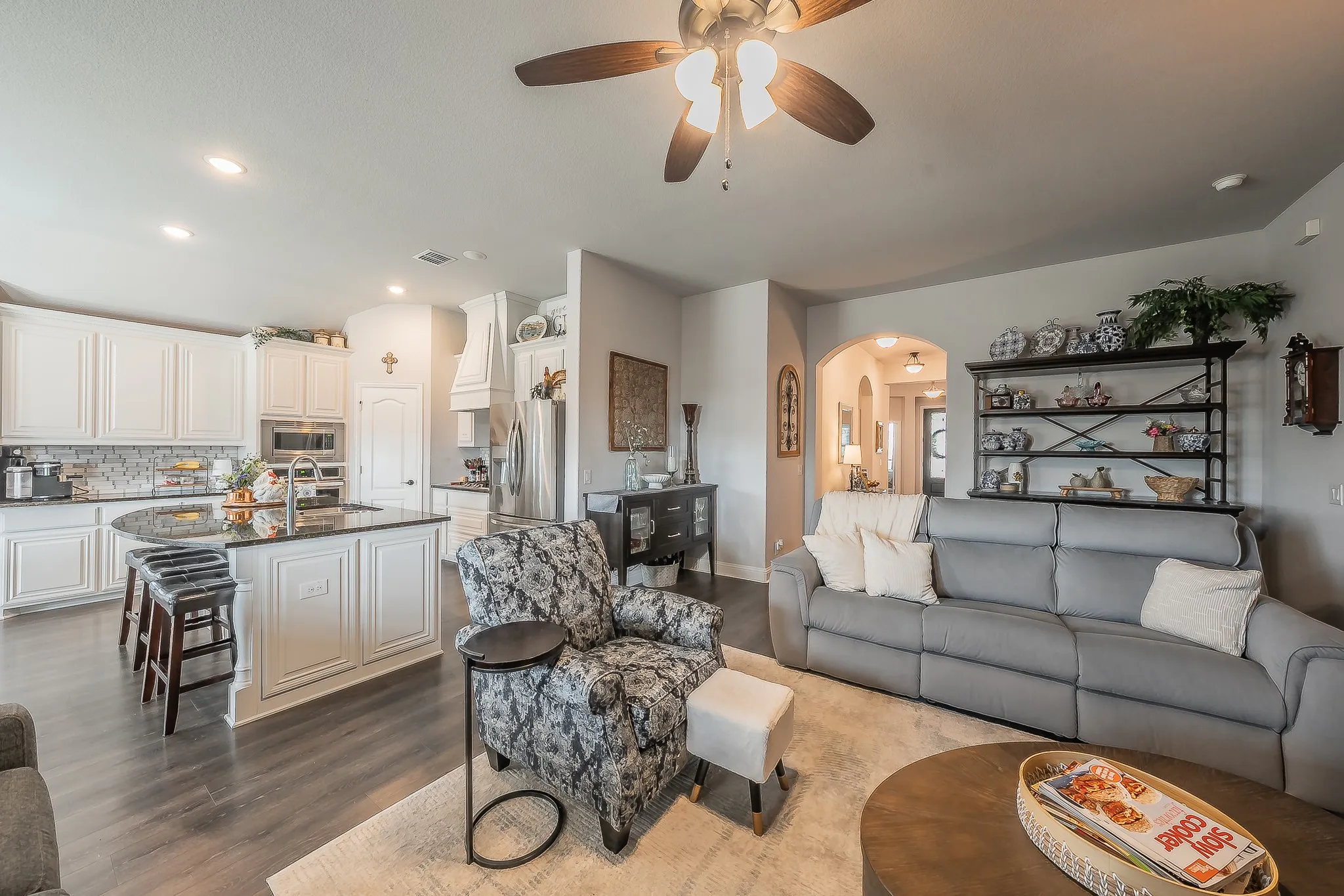 Open-concept living space featuring wood-finish flooring, a ceiling fan with integrated lighting, and recessed ceiling lights