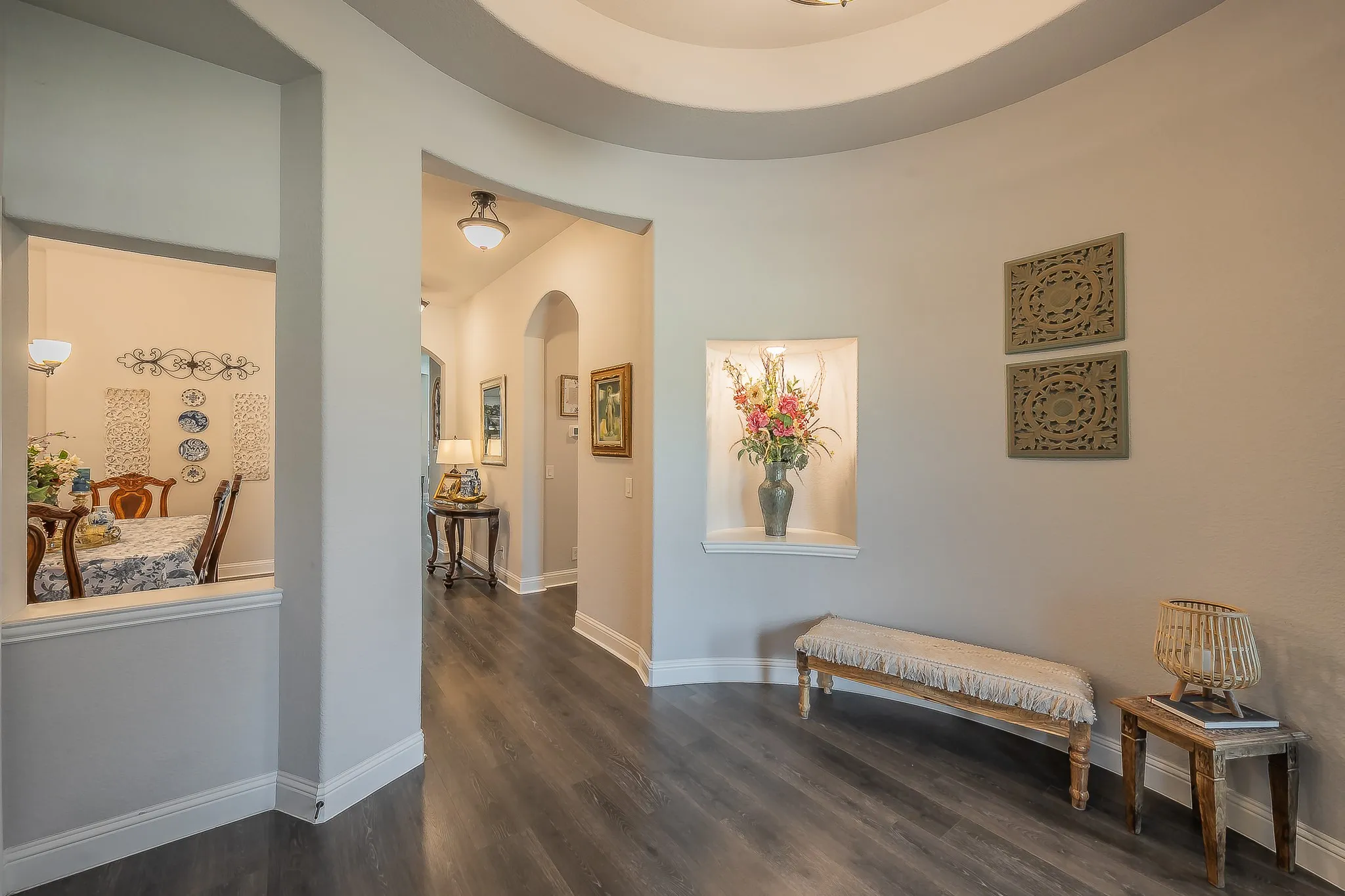 Hallway with wood-finish flooring, a curved tray ceiling, and an illuminated alcove