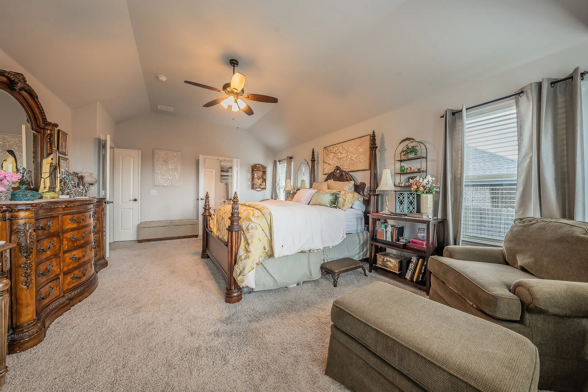 Carpeted bedroom featuring vaulted ceilings, a ceiling fan, and two windows with blinds and drapes