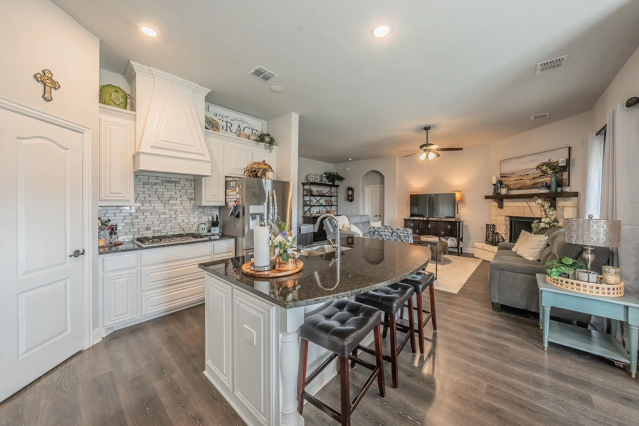 Gourmet kitchen featuring white cabinetry, a mosaic tile backsplash, stainless steel appliances, and a curved island with seating
