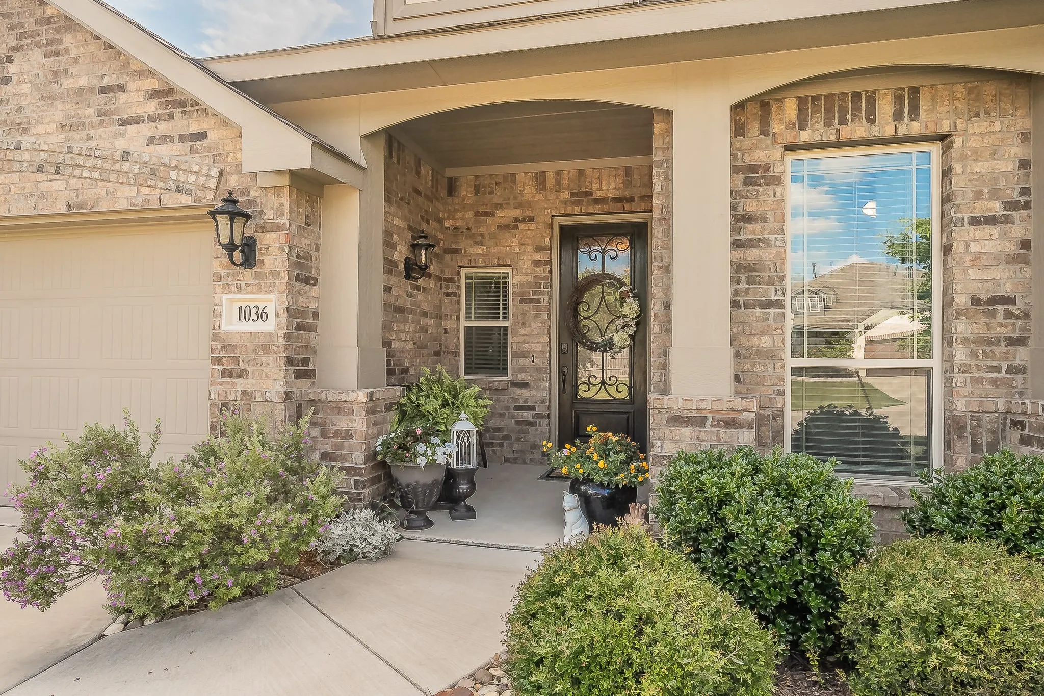 Brick facade entry featuring an arched portico, decorative glass front door, and a prominent picture window