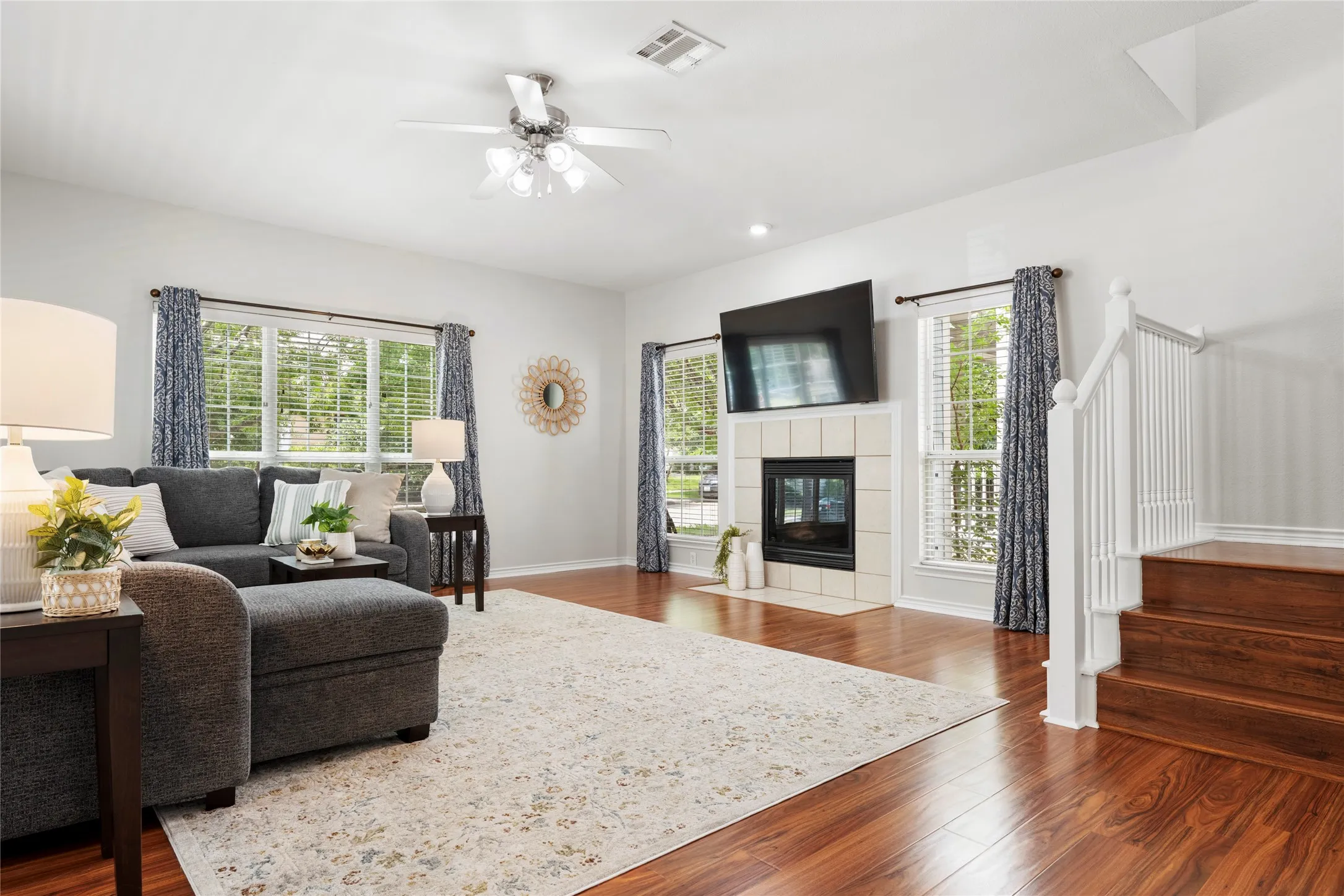 Inside, the entry opens to a spacious living room filled with natural light from an abundance of windows. A cozy fireplace serves as the focal point, creating a comfortable gathering space for everyday living and entertaining alike. Easy-care wood-look flooring flows throughout the main living areas and continues into every bedroom, offering both style and durability with no carpet anywhere in the home.