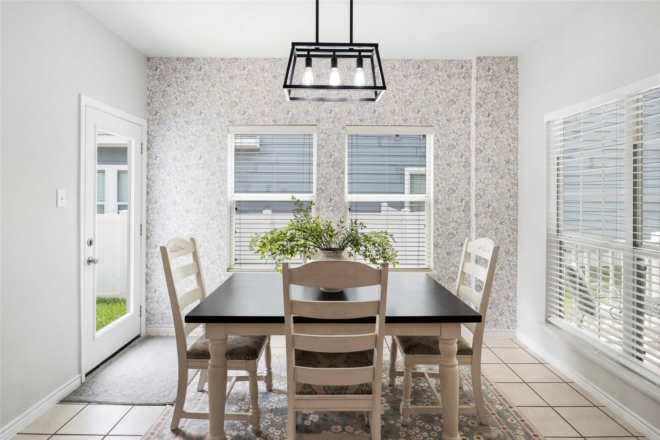 The dining area enjoys windows that frame views of both the front porch and backyard, while a designer wallpaper accent wall adds character and charm.