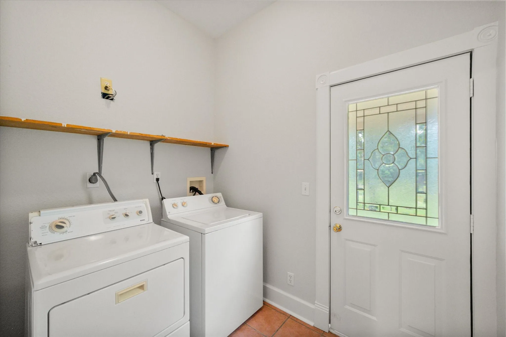 Utility room with washer, dryer, storage, and exterior access in a practical country farmhouse layout.