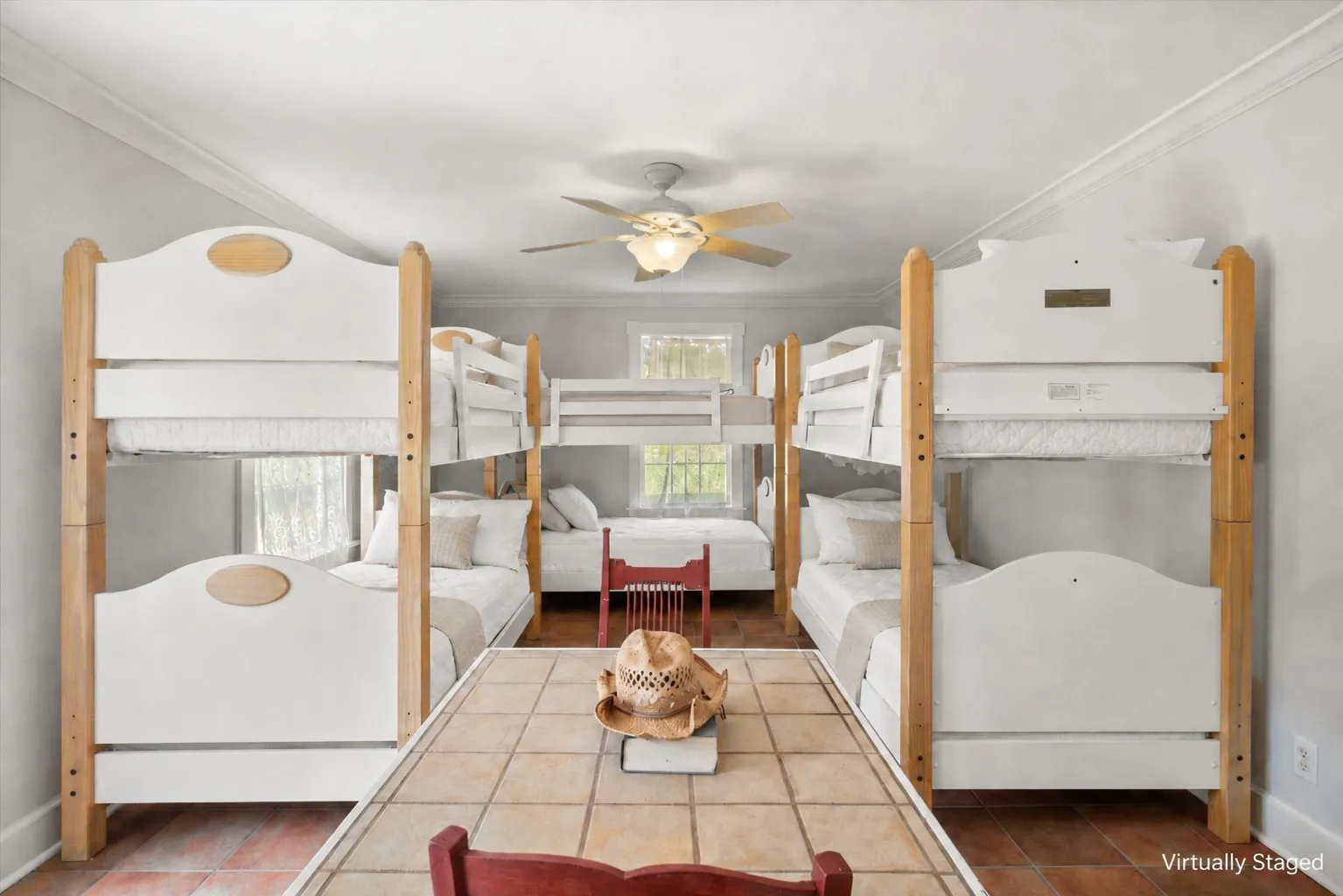 Bunkroom with three bunk beds, neutral farmhouse bedding, and room for family or guests.