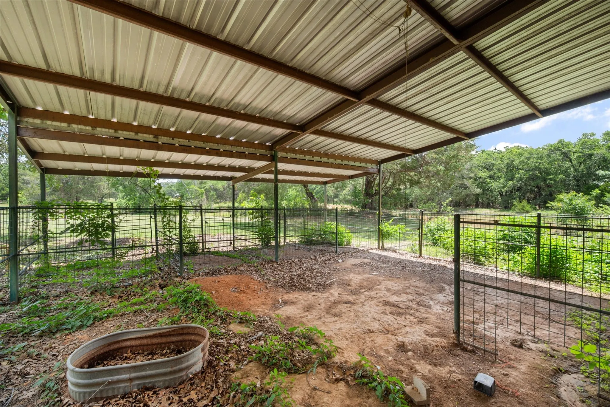Covered livestock area with fencing, shade, and functional setup for horses, cattle, or small farm use.