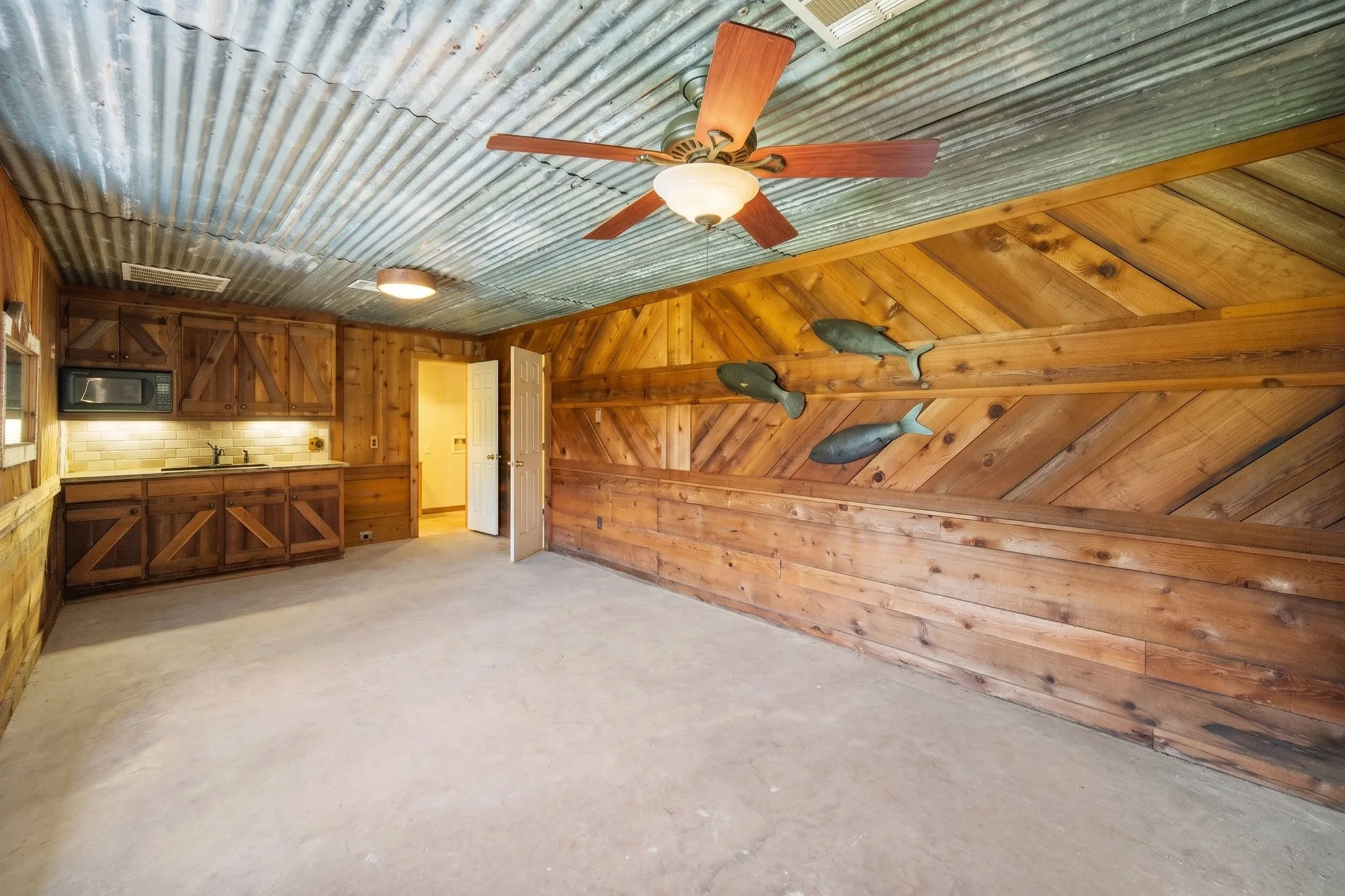 Rustic barn apartment interior with kitchenette, wood paneling, and corrugated ceiling on 42-acre Kerens ranch.
