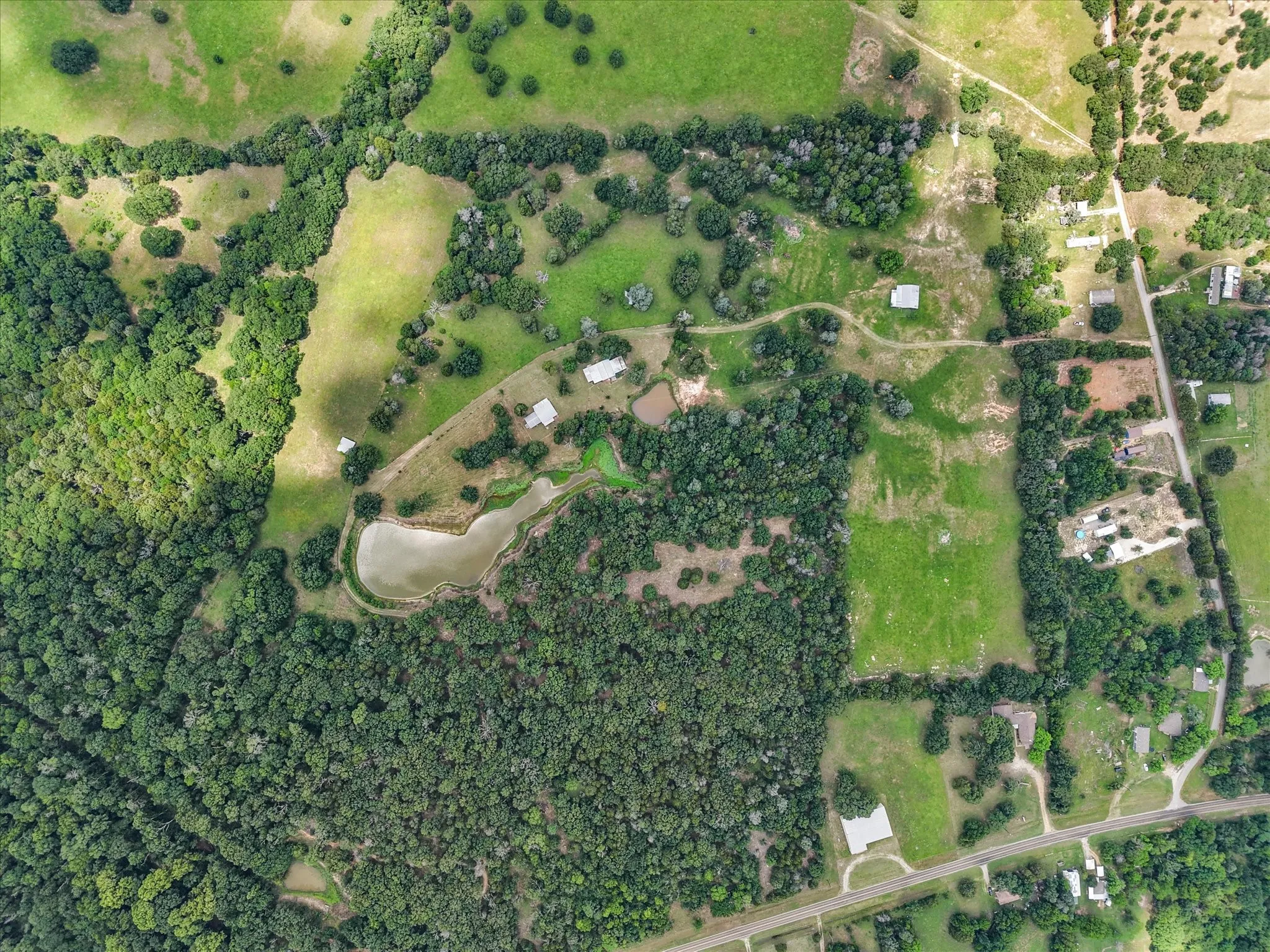Aerial boundary view showcasing 42.199 acres with farmhouse, wooded areas, pasture, and private pond.