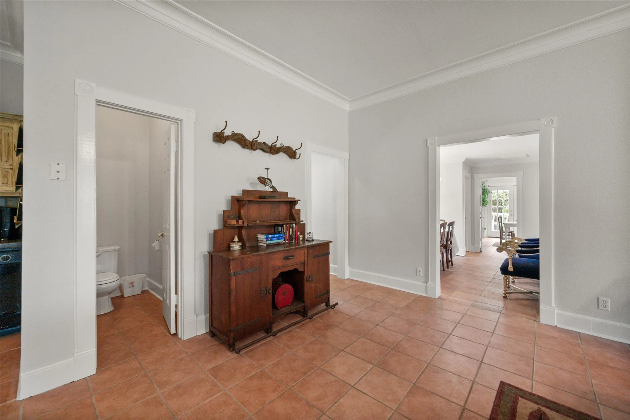Interior with tile flooring, neutral walls, and classic farmhouse flow between living areas and bedrooms.