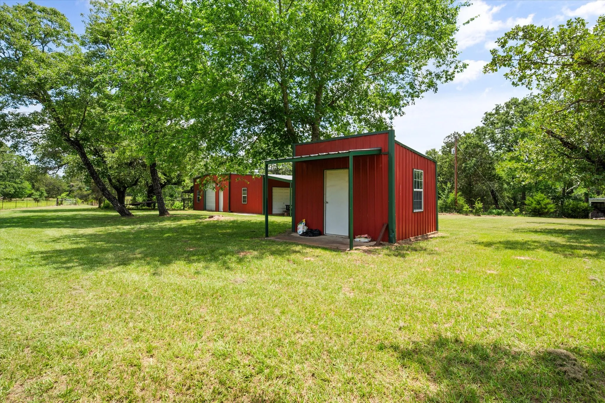 Red outbuilding and open acreage provide extra storage and utility on this Kerens TX farm and ranch property.