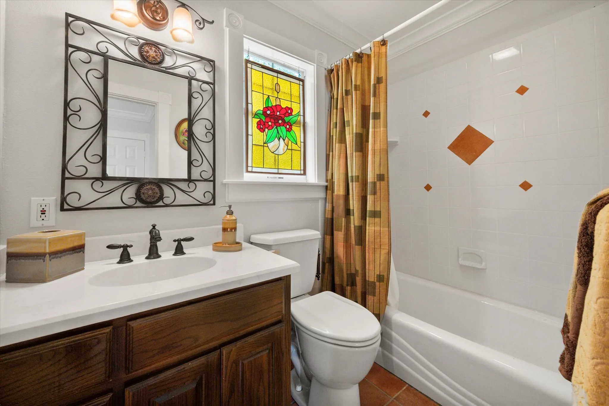 Full bathroom with tub-shower combination, stained glass window, and farmhouse-style vanity.