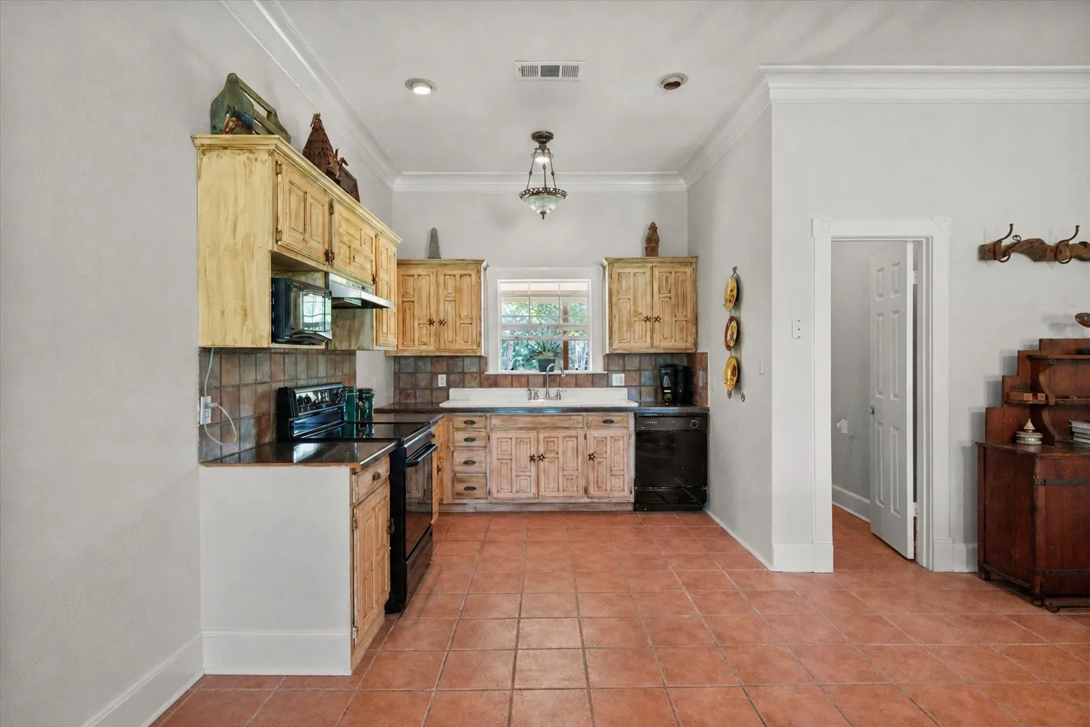 Rustic farmhouse kitchen with wood cabinetry, tile floors, and classic country charm inside this 42-acre Kerens TX farm and ranch home.