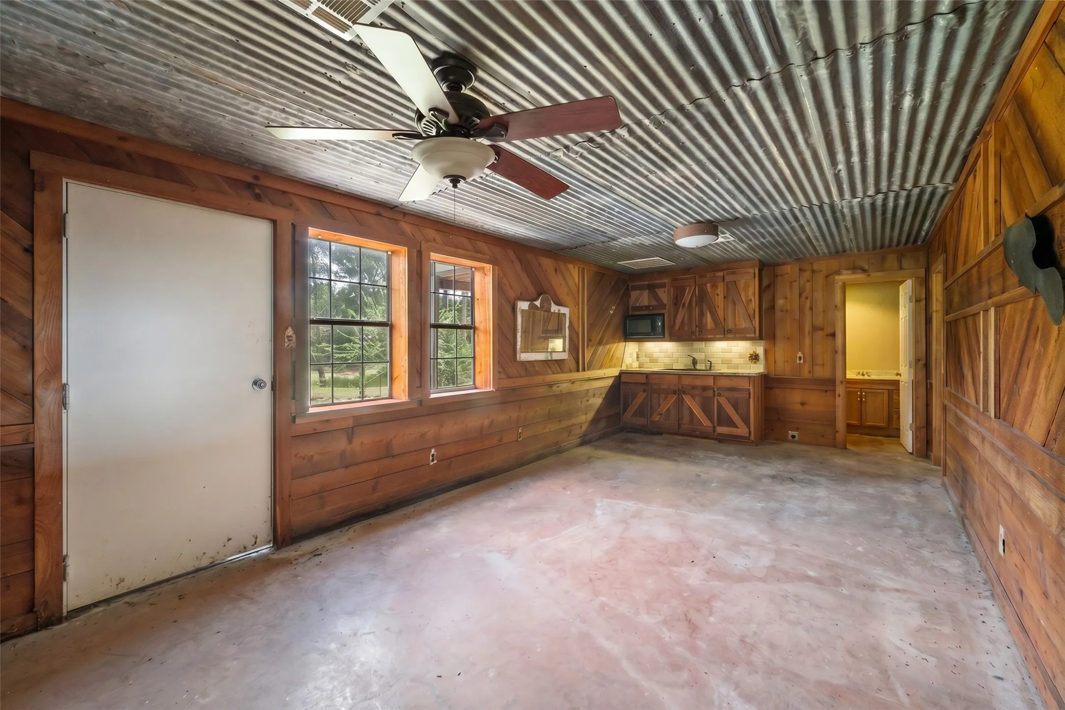 Efficiency apartment inside barn with rustic wood walls, kitchenette, and flexible guest or ranch-hand space.