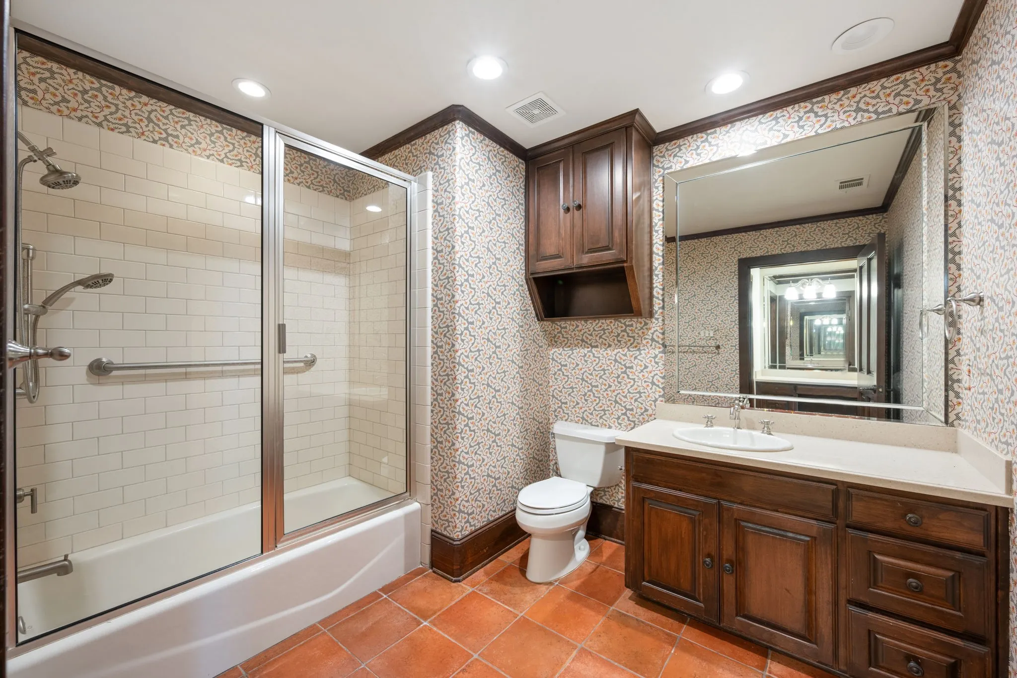 First floor full bathroom featuring a tub/shower combination with subway tile surround, clear glass enclosure, and grab bar