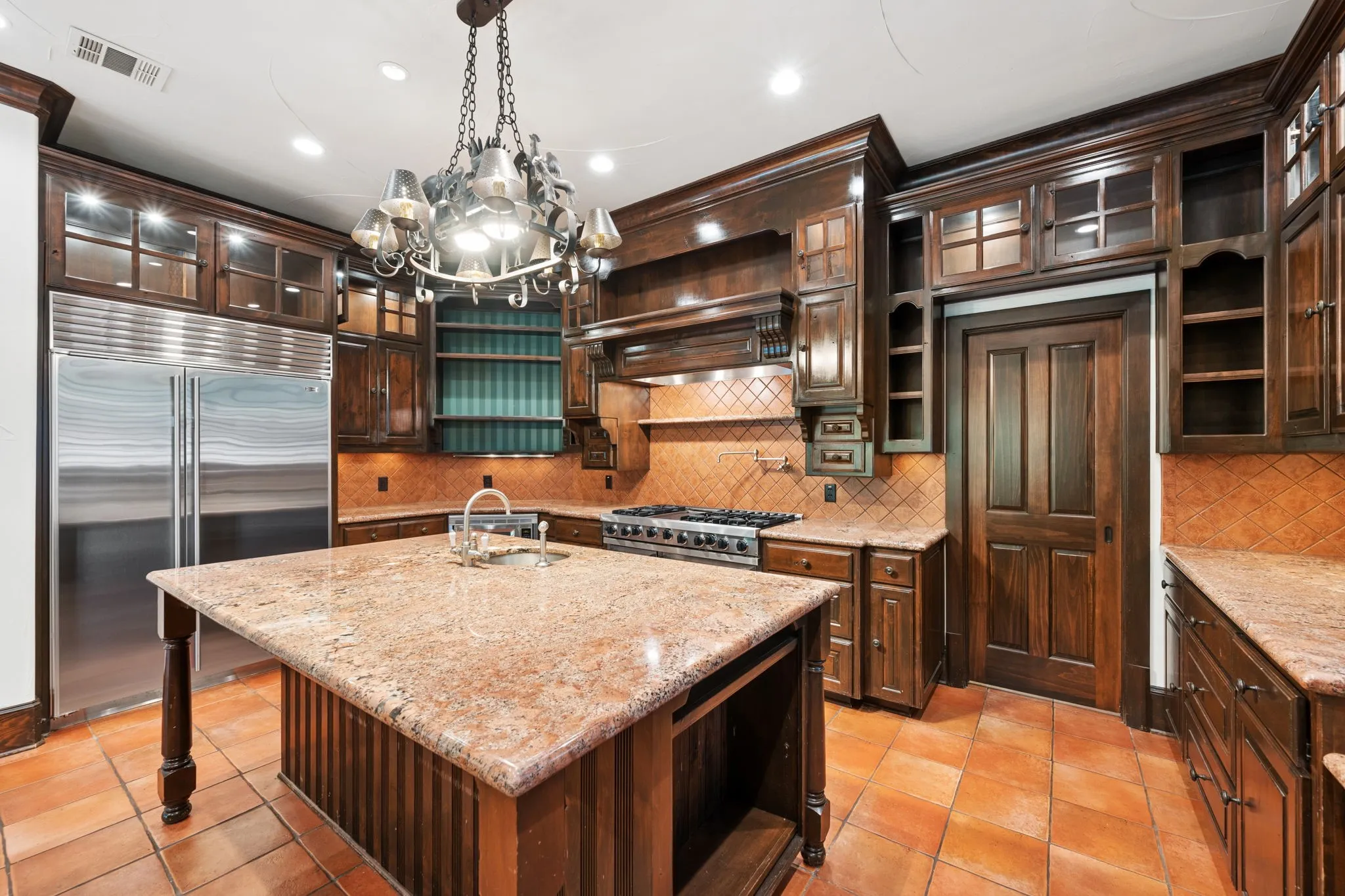 Kitchen featuring rich wood cabinetry, a central island with a stone countertop, and a stainless steel refrigerator
