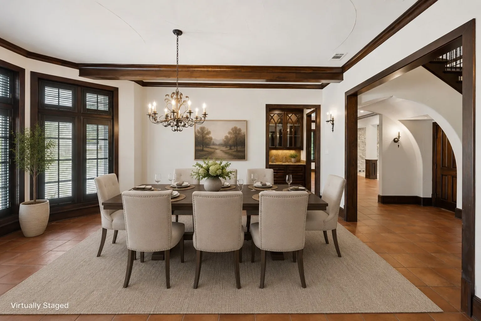 Formal dining area featuring terracotta tile flooring, exposed wood ceiling beams, and dark wood trim