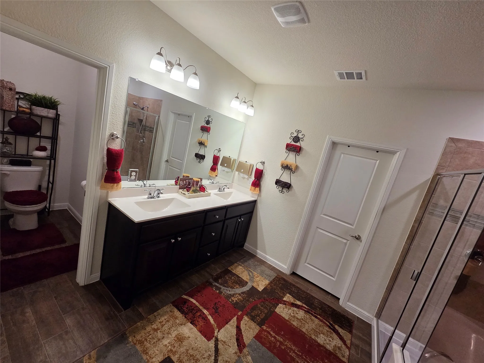 Double vanity with integrated sinks, dark wood-finish cabinetry, and overhead lighting fixtures