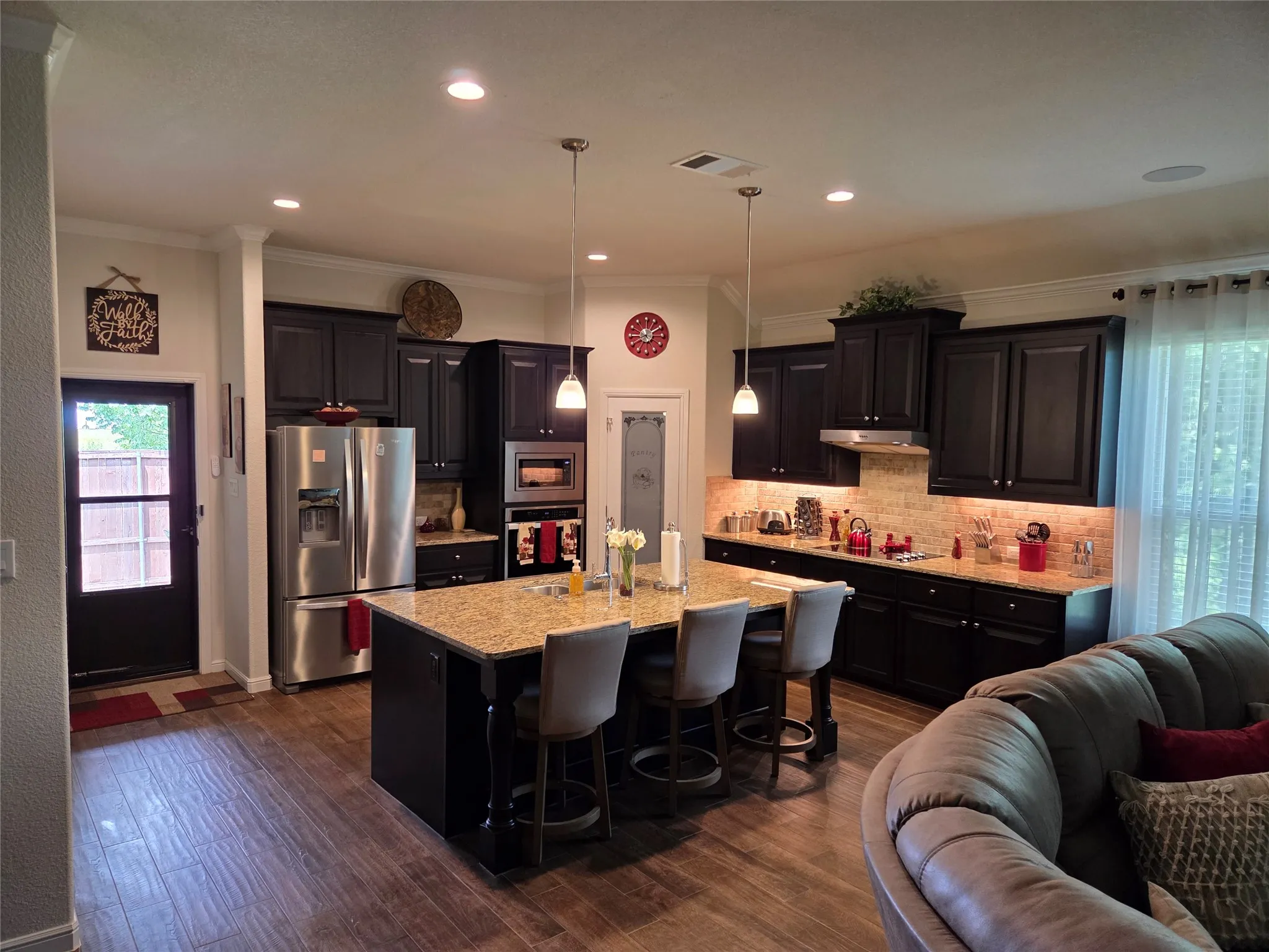 Kitchen featuring dark wood cabinetry, a large kitchen island with a stone countertop, and wood-finish flooring