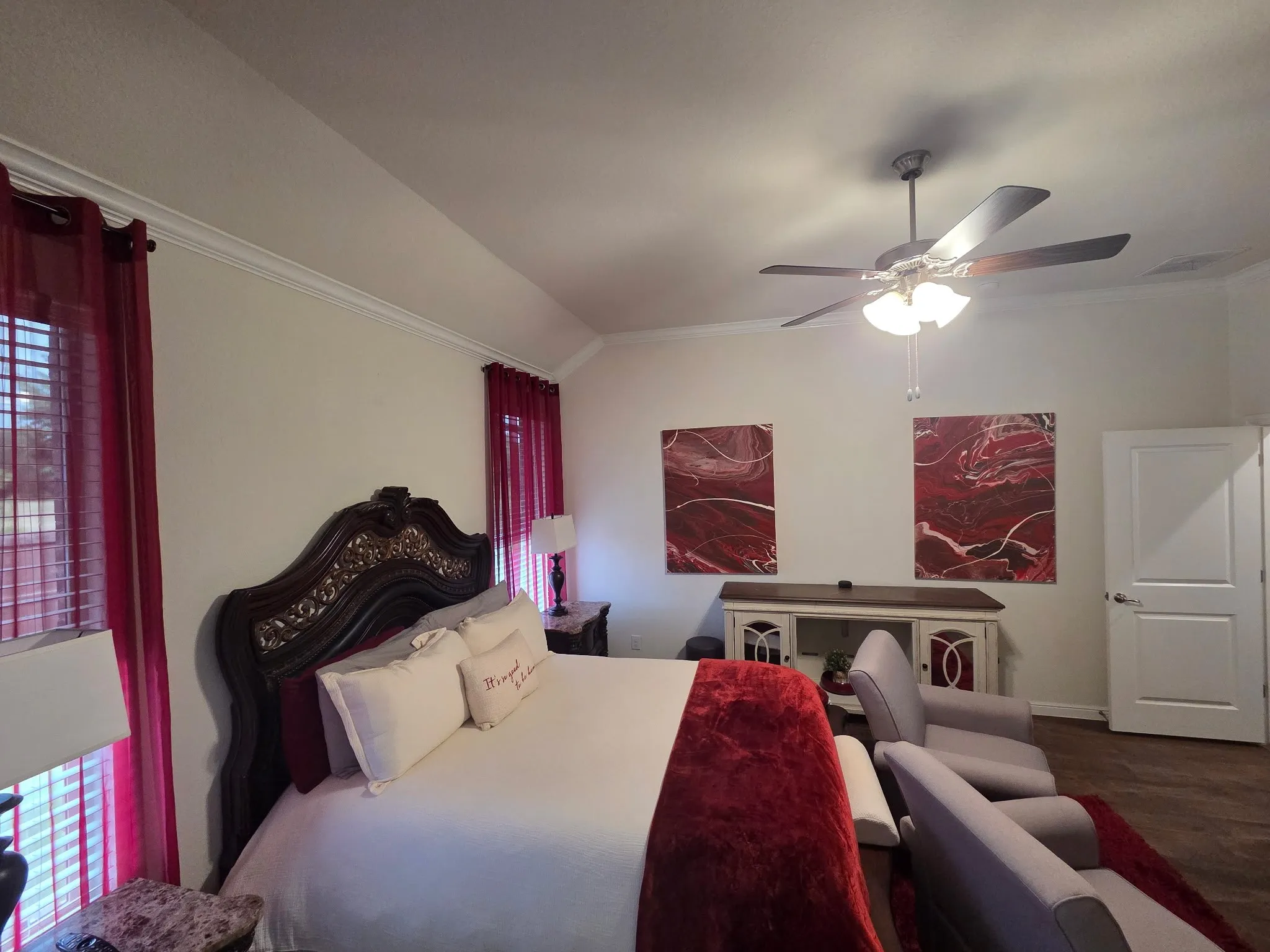 Vaulted ceiling with crown molding, ceiling fan with integrated lighting, wood-finish flooring, paneled interior door, and window with blinds