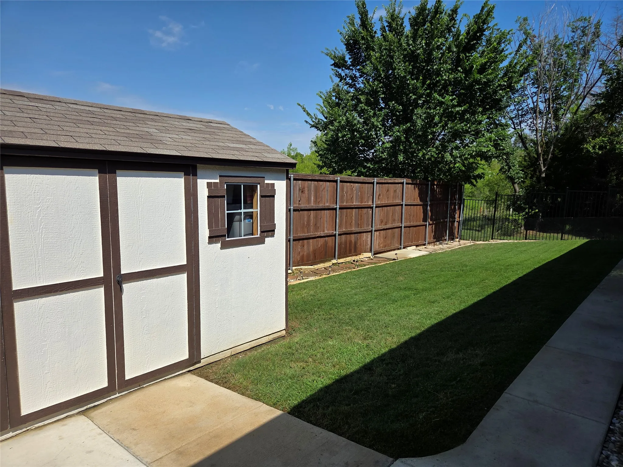 Detached storage shed with a shingle roof and decorative window shutters