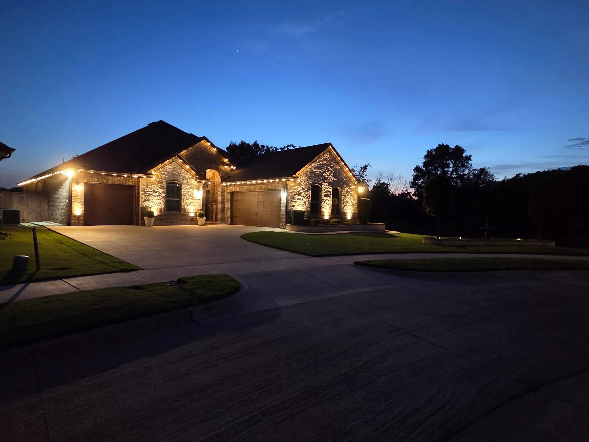 Stone exterior featuring a three-car garage and manicured landscaping