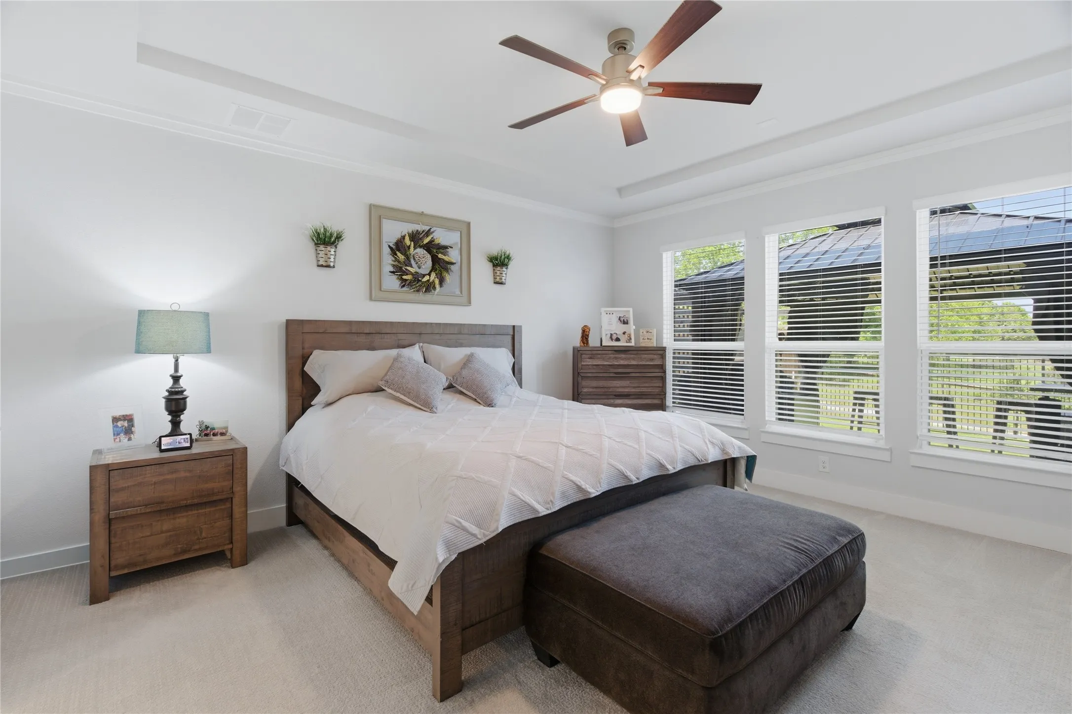 Primary bedroom featuring a tray ceiling with crown molding, a five-blade ceiling fan with integrated lighting, and white walls