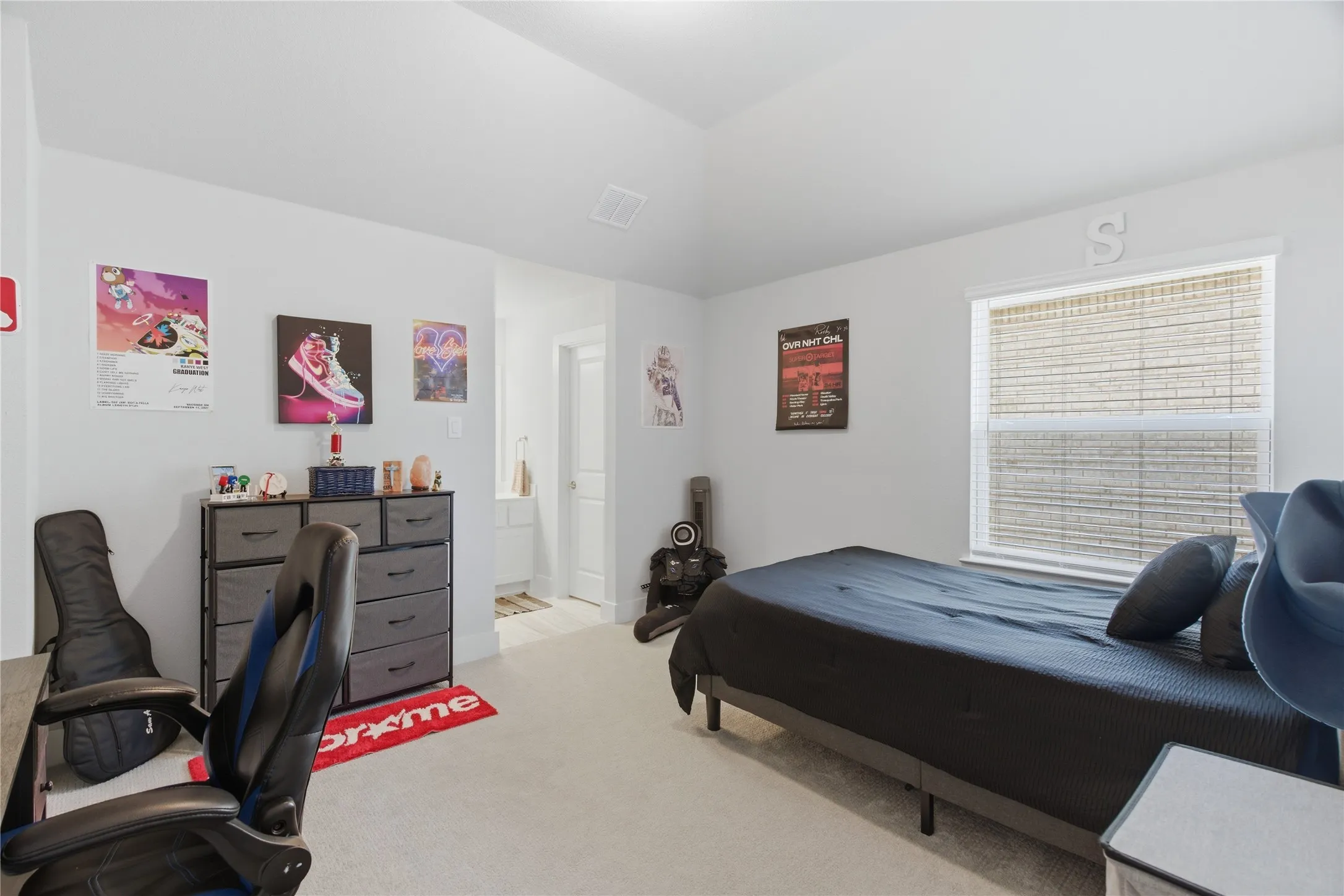 Upstairs carpeted bedroom featuring a single window with horizontal blinds, a neutral wall color, and a vaulted ceiling