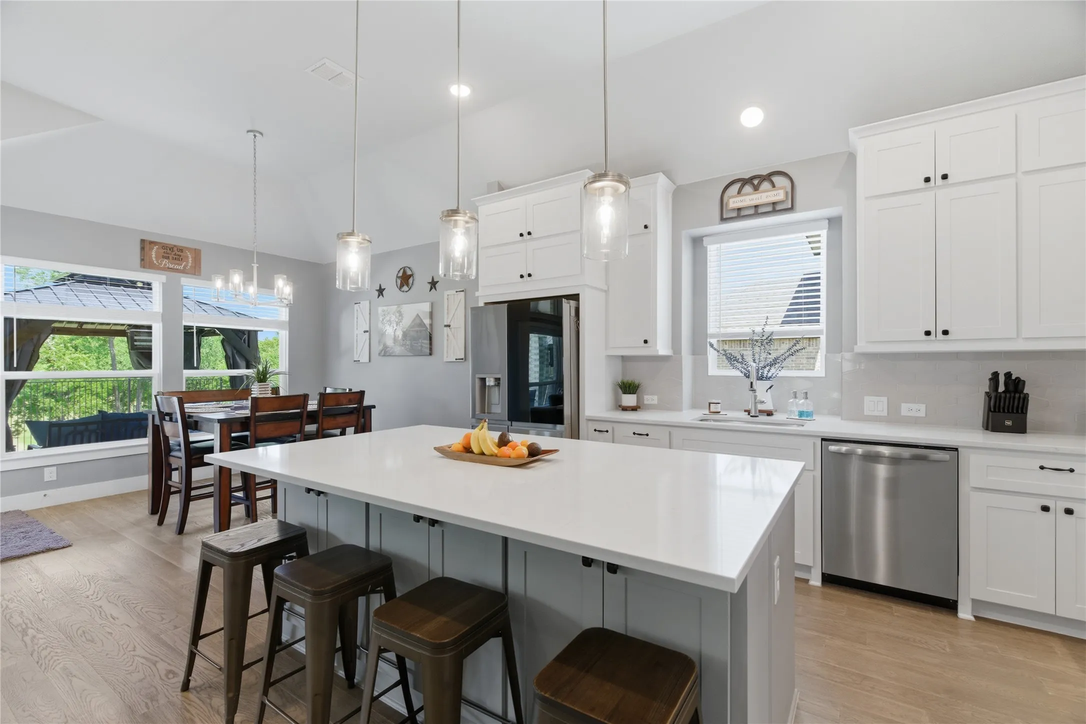 Kitchen featuring a large central island with seating, white shaker-style cabinetry, and stainless steel appliances