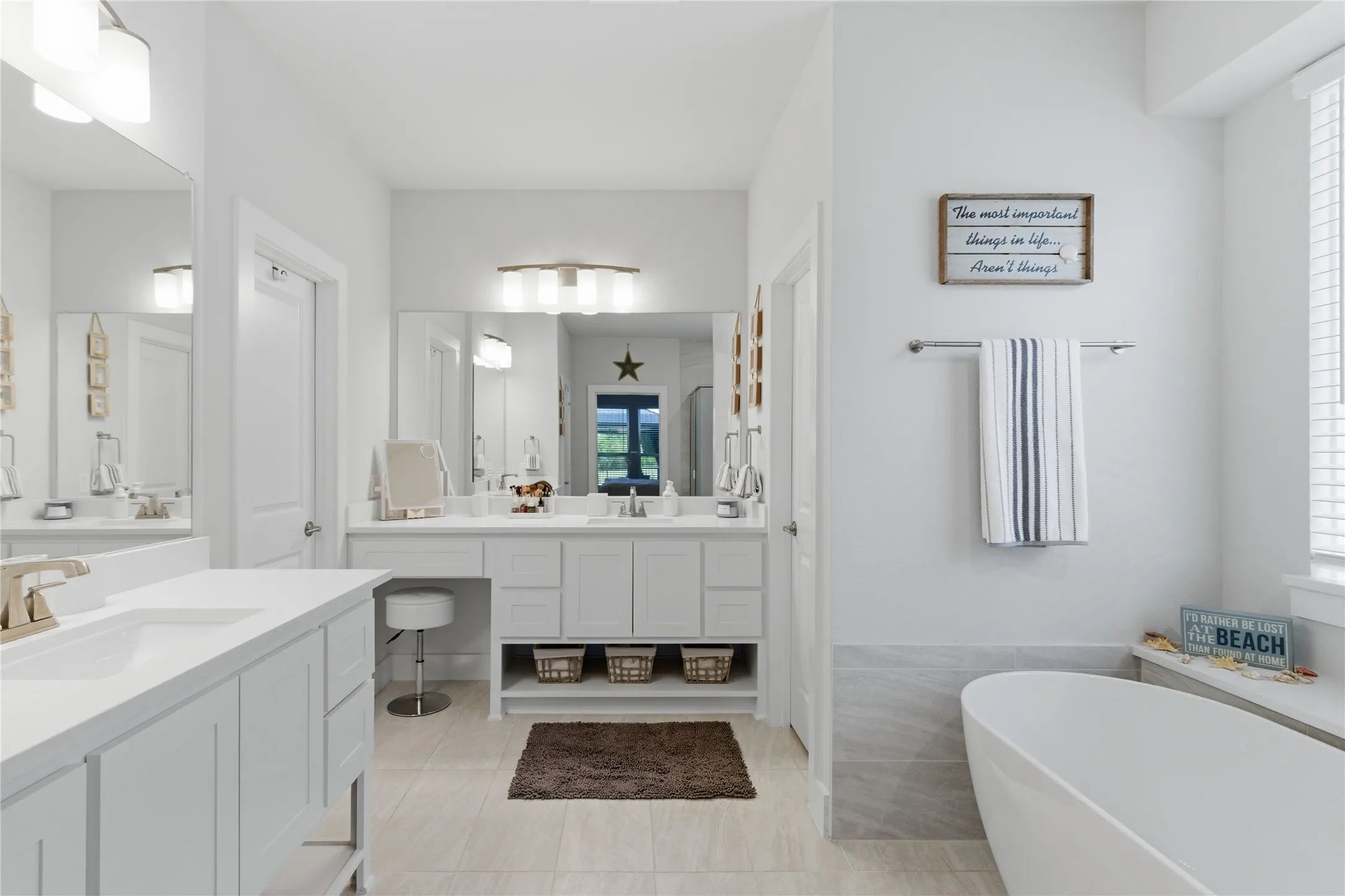 Primary bathroom featuring a freestanding soaking tub, dual vanity with undermount sinks, and a dedicated vanity seating area