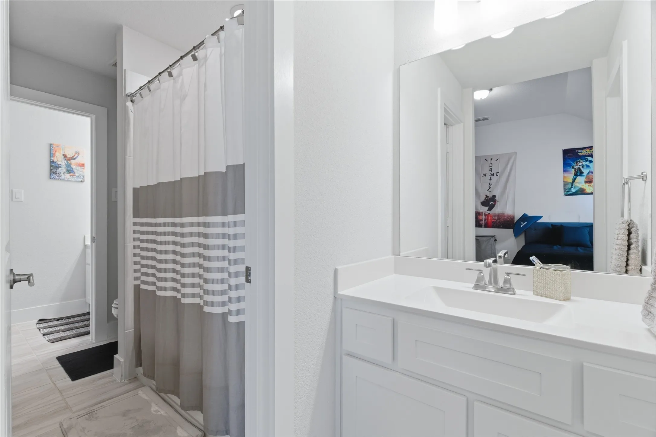 Bathroom featuring a white vanity with an integrated sink, chrome faucet, and expansive wall mirror