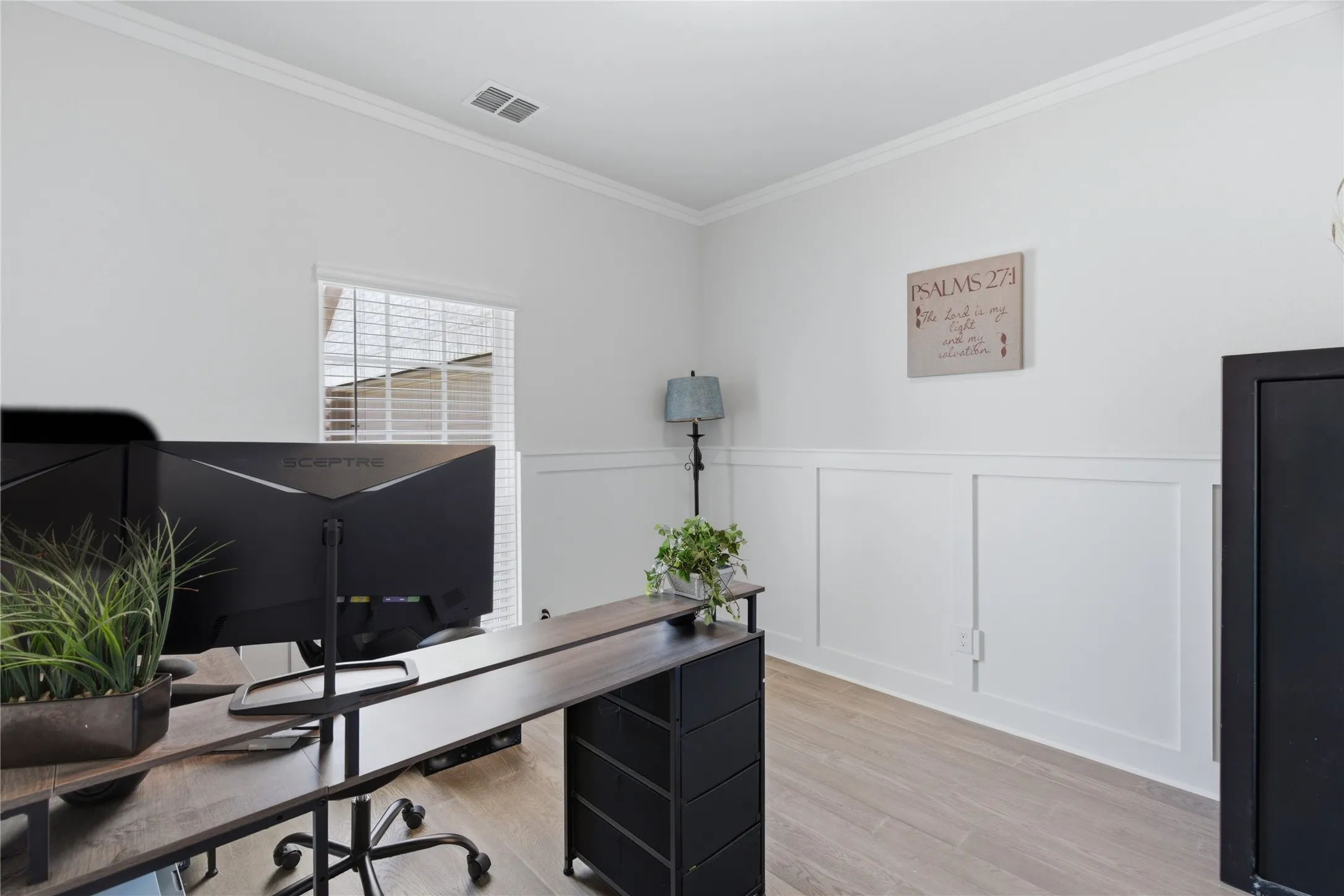 Room featuring light-toned wood-finish flooring, white walls, and wainscoting