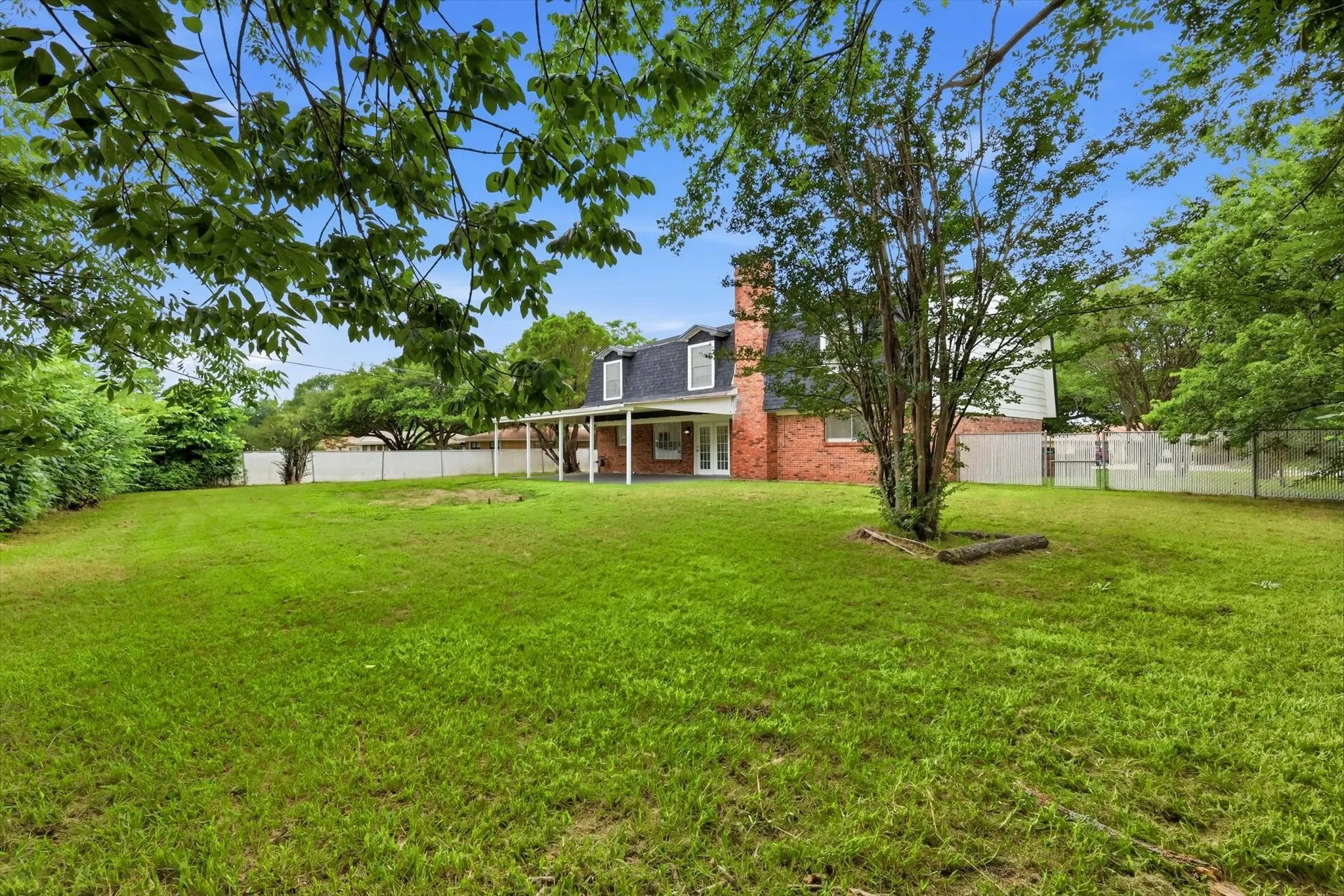 Expansive green lawn with a white picket fence enclosing the perimeter