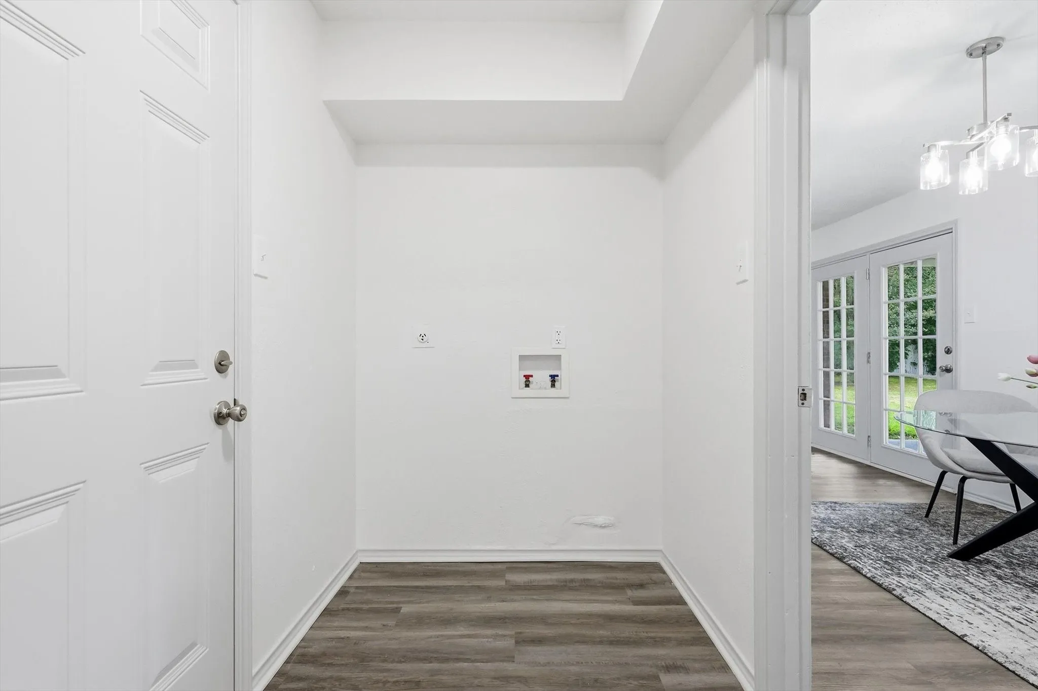 Utility alcove featuring wood-finish flooring and a white paneled door
