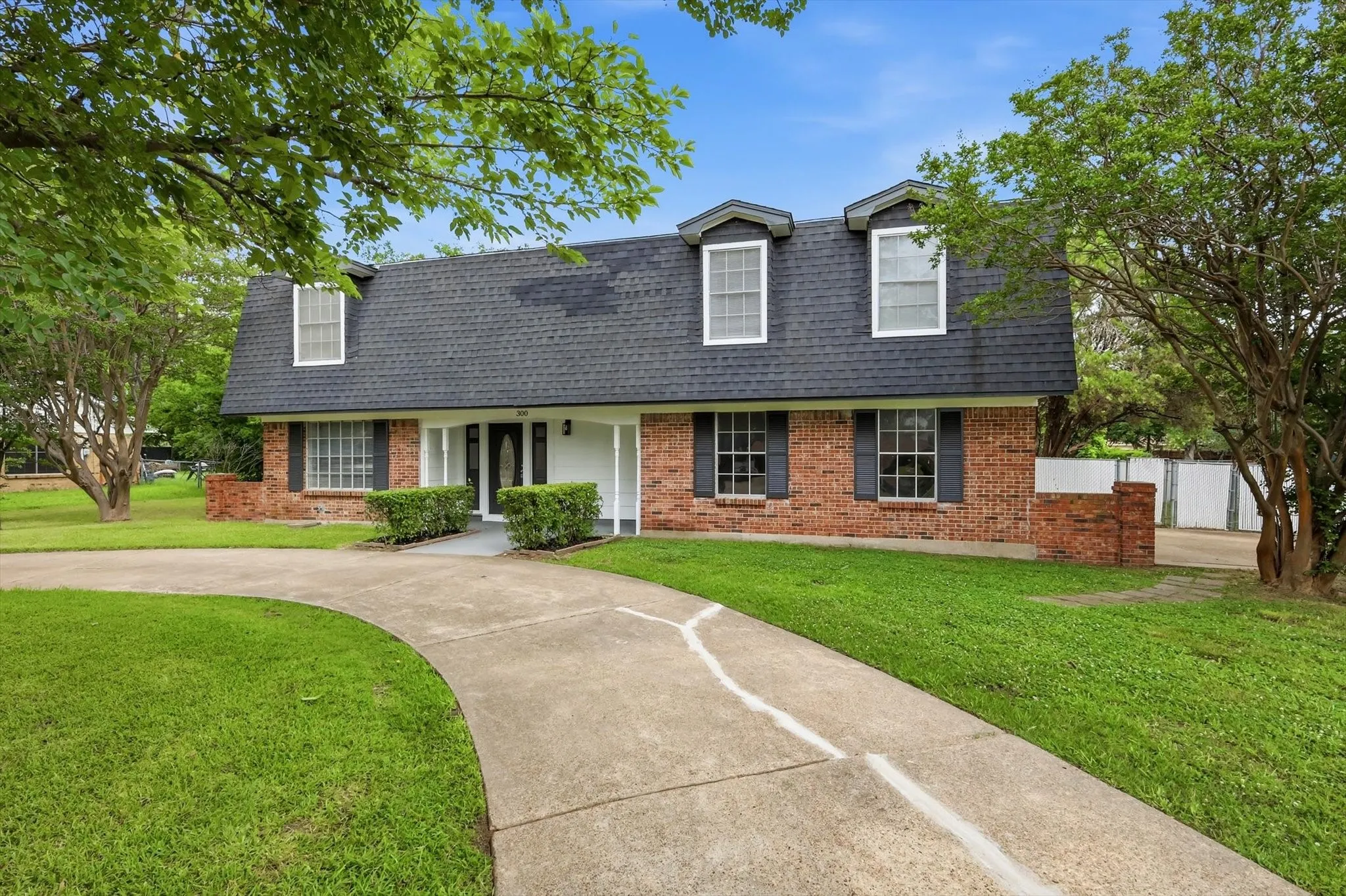 Brick facade residence with a dark shingle roof and dormer windows
