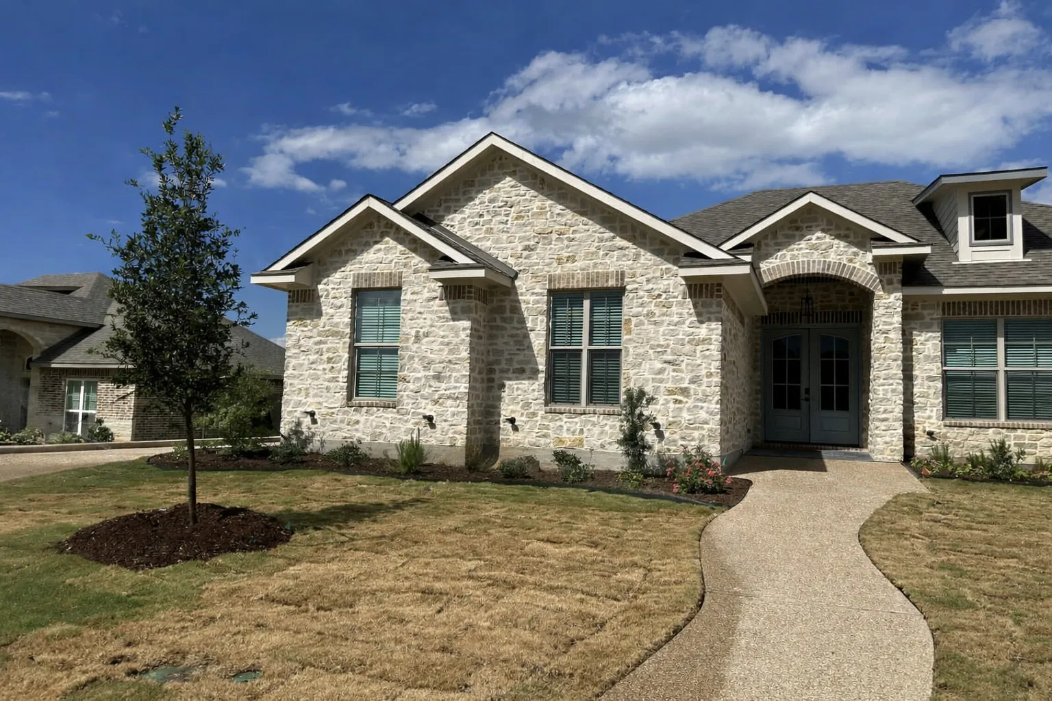Stone veneer exterior with brick accents and multiple gables