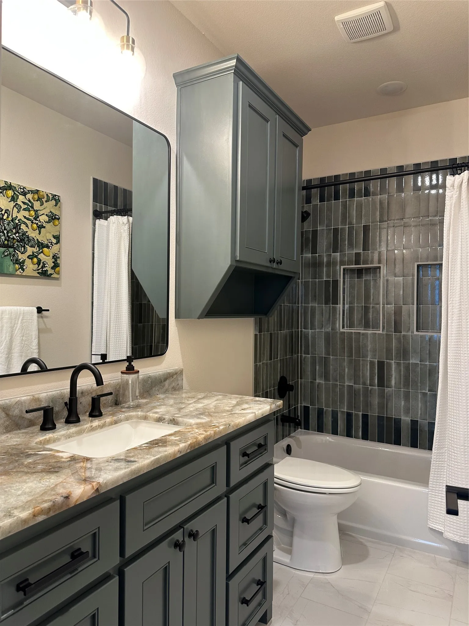 Modern bathroom featuring a rectangular undermount sink set in a patterned stone countertop, paired with a dark-finish faucet