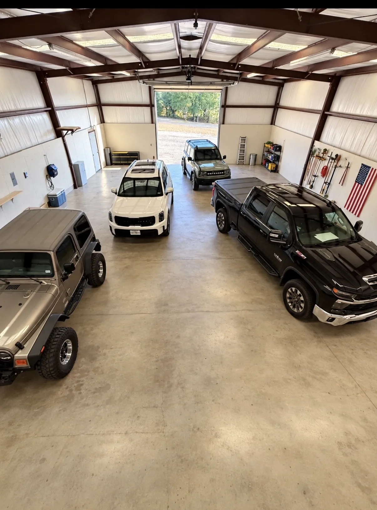 Spacious garage with high ceilings,  roll-up door, concrete flooring, and exposed metal beams