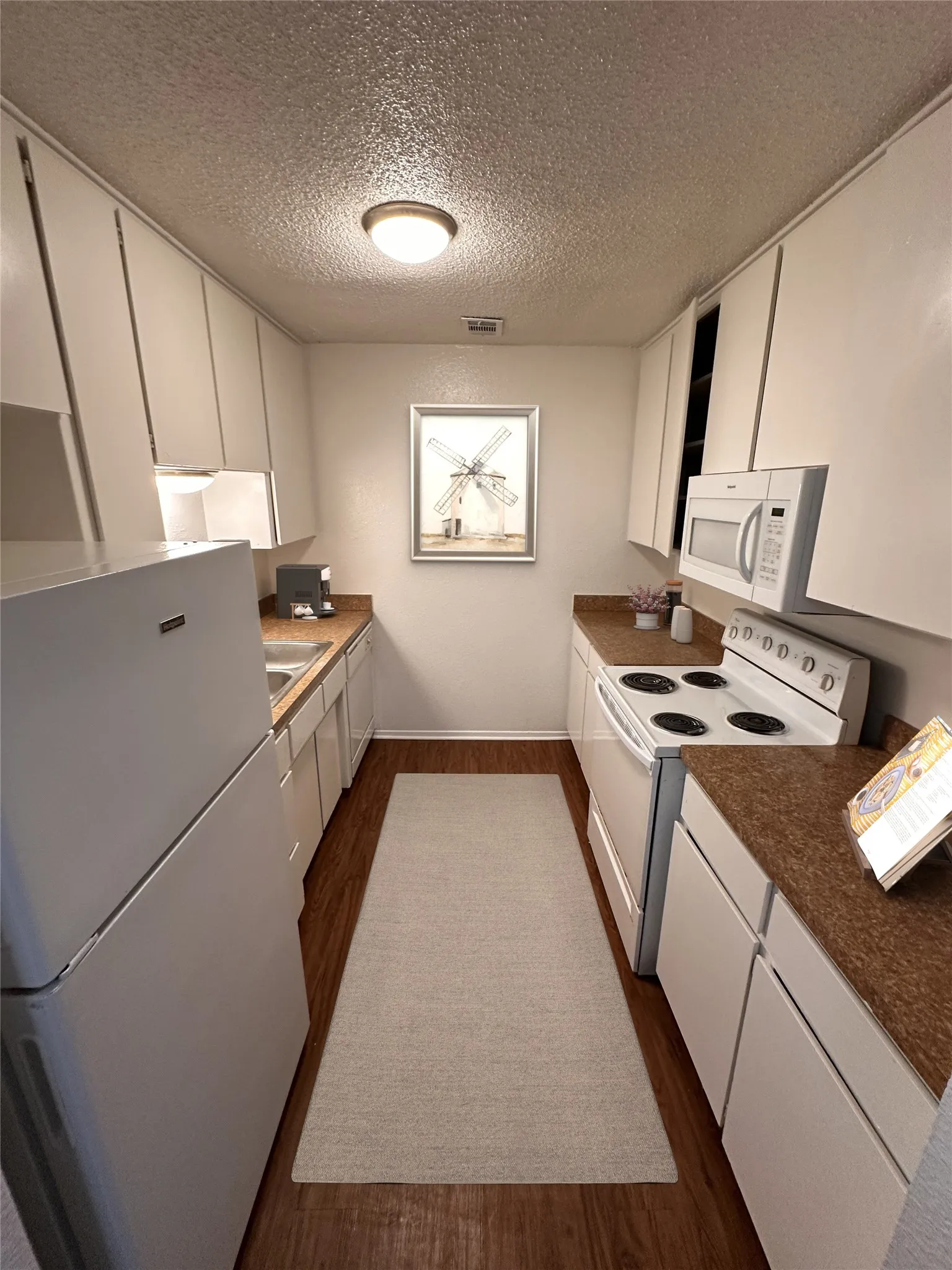 Kitchen with refrigerator, oven, stove, microwave and garbage disposal