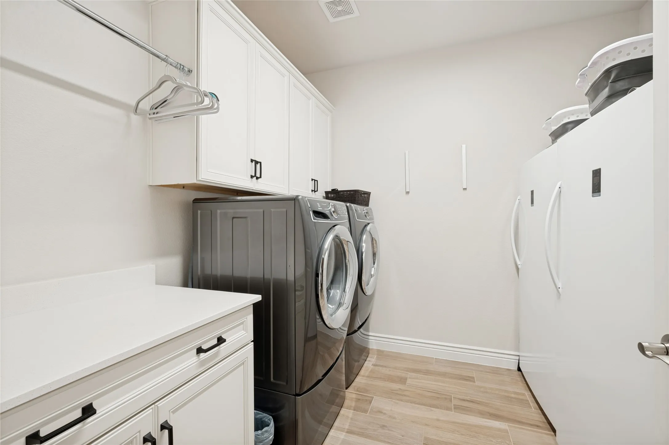 Laundry with lots of built in cabinets and a custom utility closet behind the door.