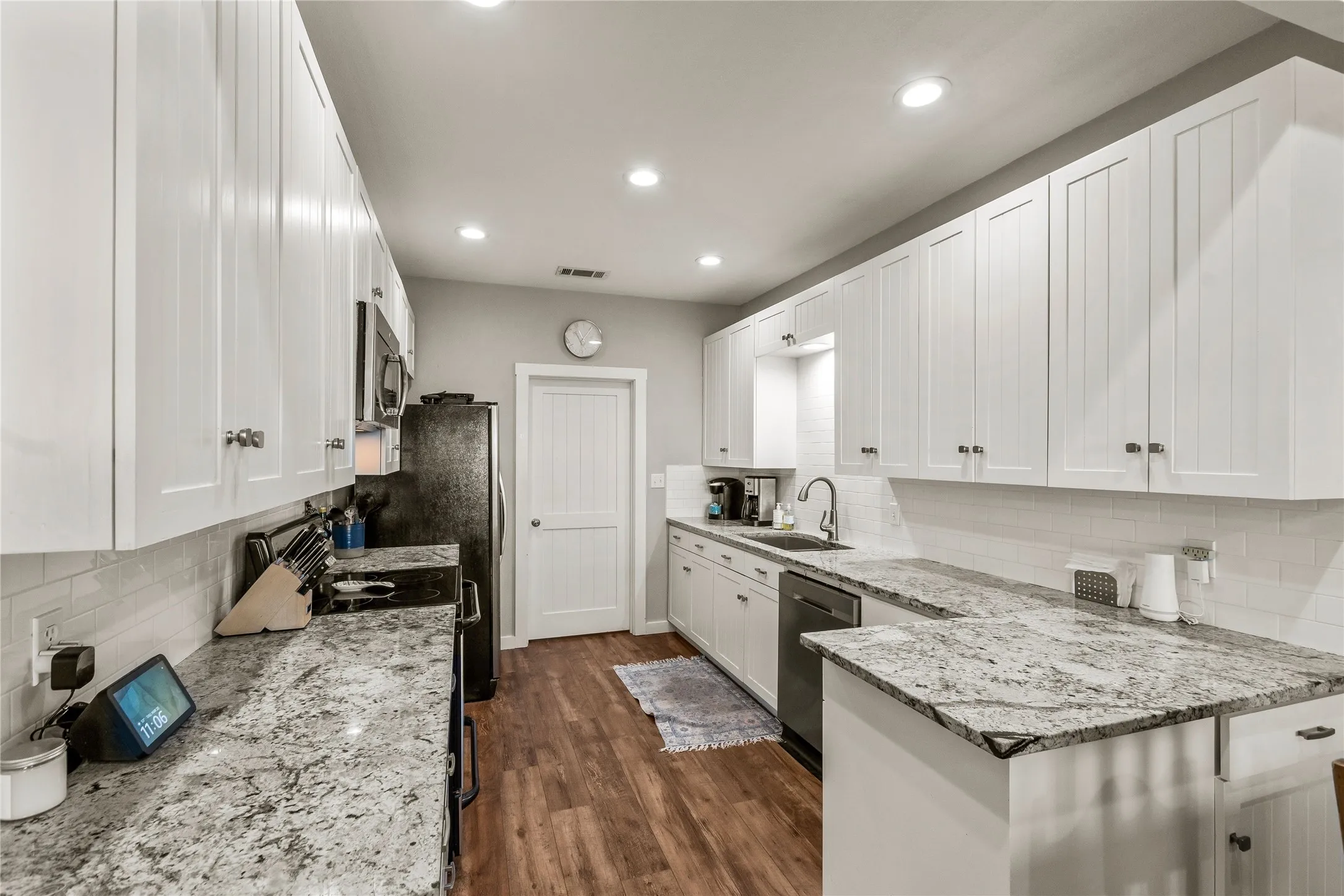 Kitchen with white cabinets, light stone counters, tasteful backsplash, and recessed lighting