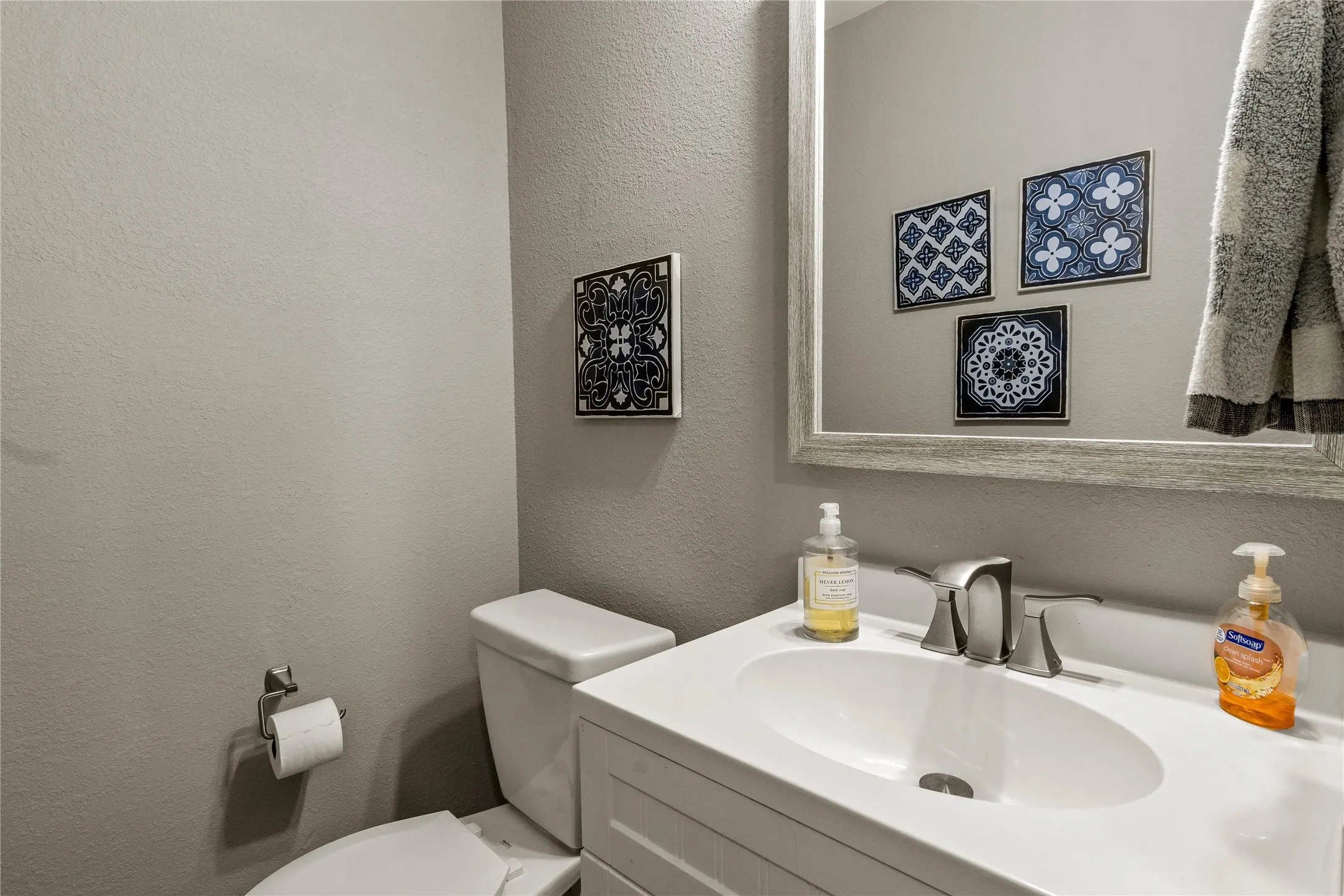 Half bath with a textured wall and vanity