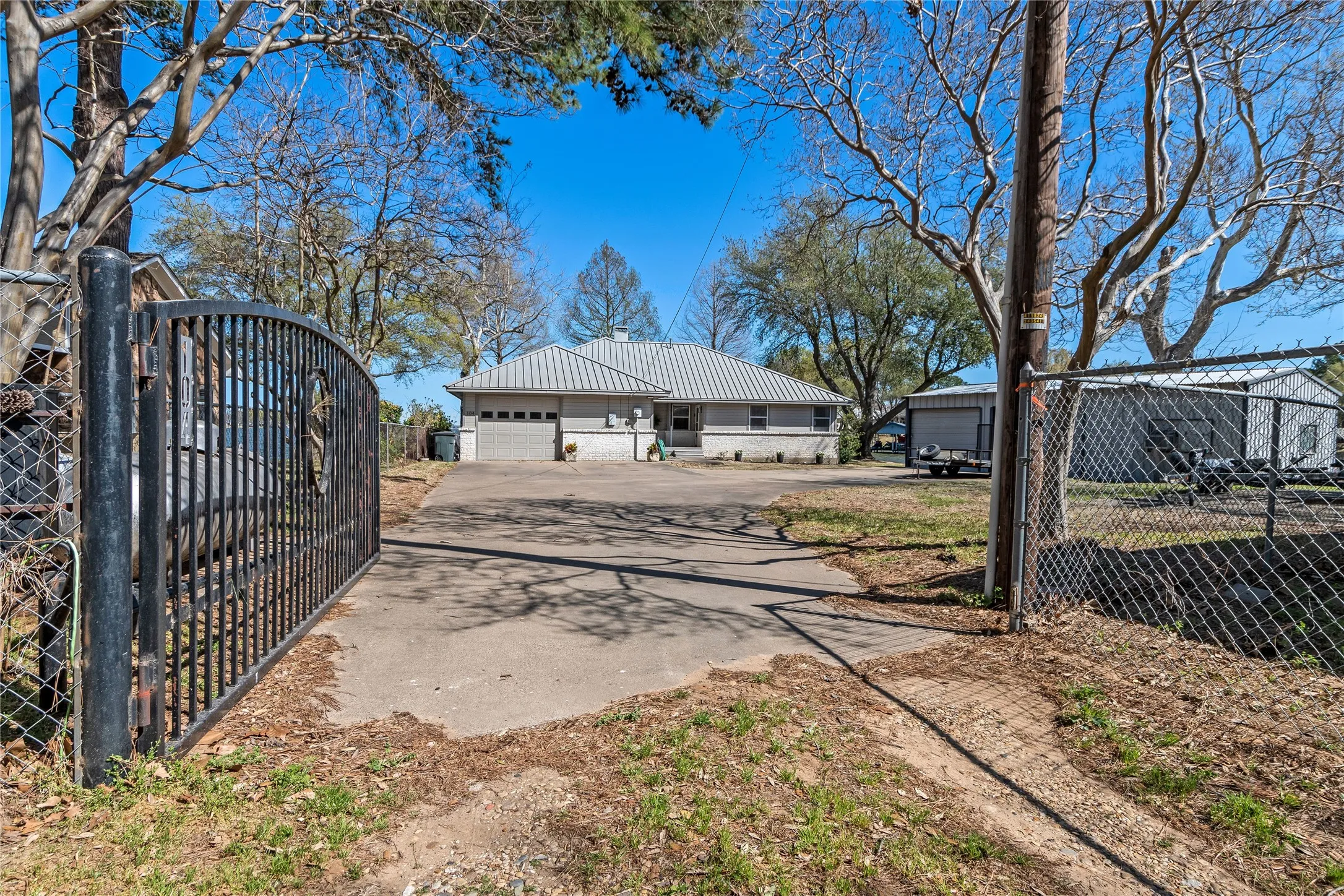 Back of property featuring a gate, a garage, a metal roof, and brick siding